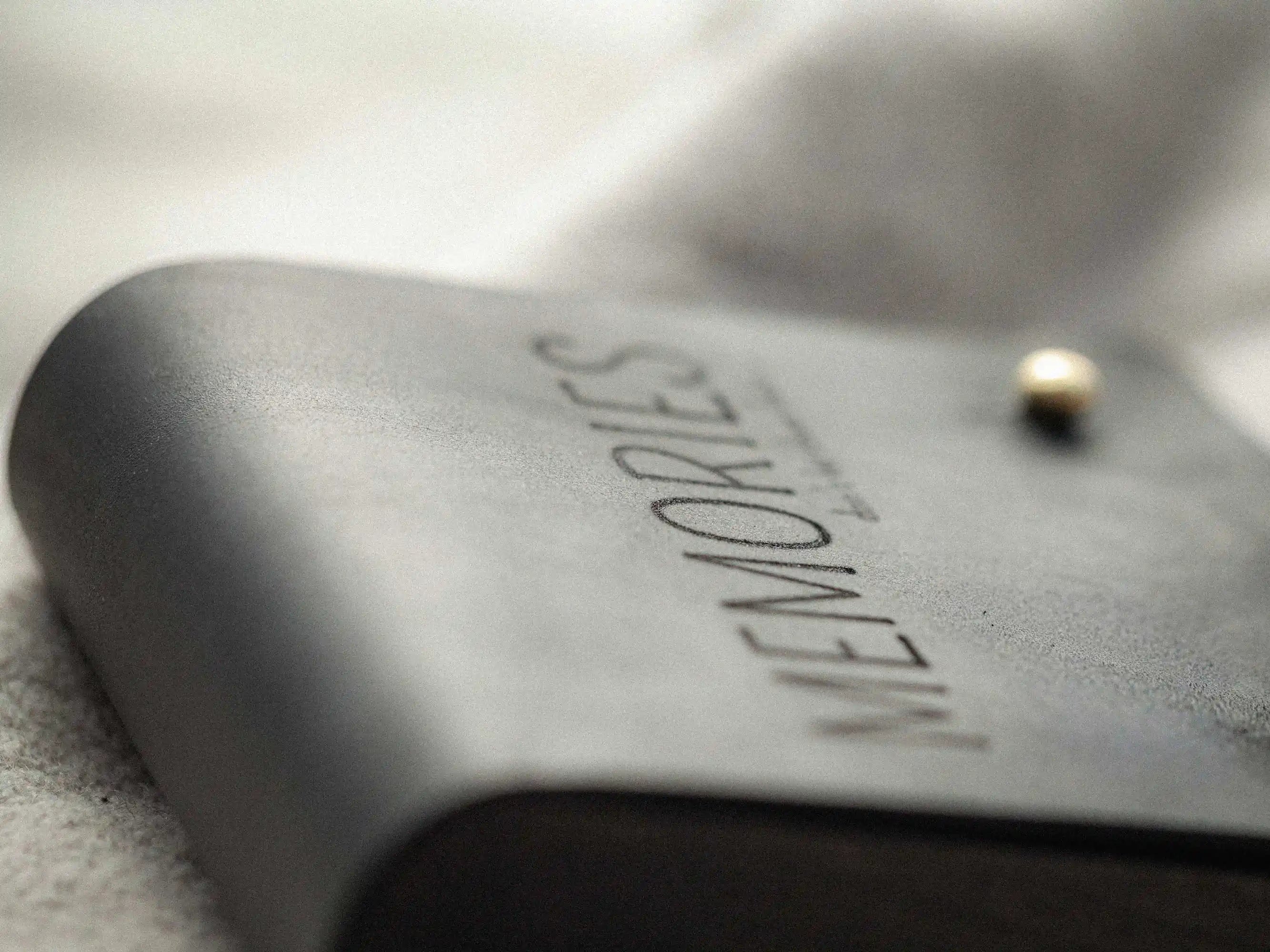 Angled close-up of black leather USB box showing curved wooden side and brass stud