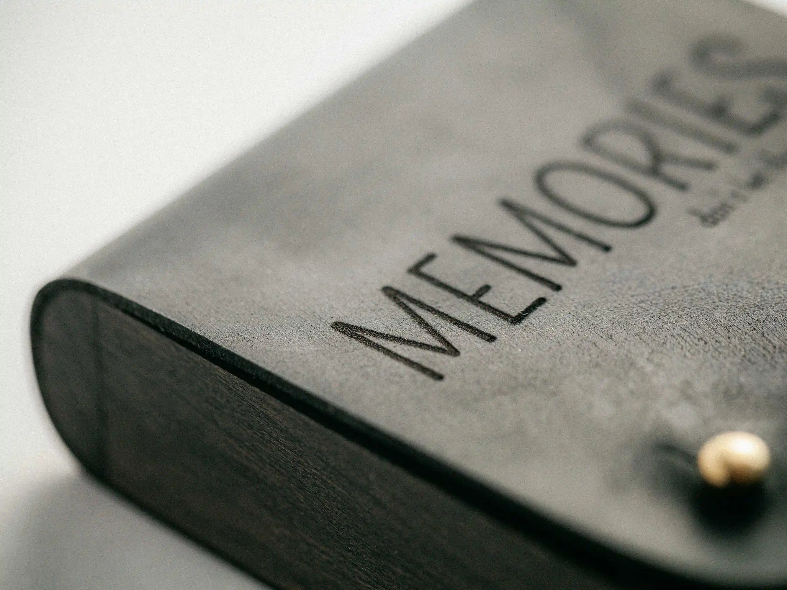 Close-up of black leather lid with “MEMORIES” engraving and brass stud detail