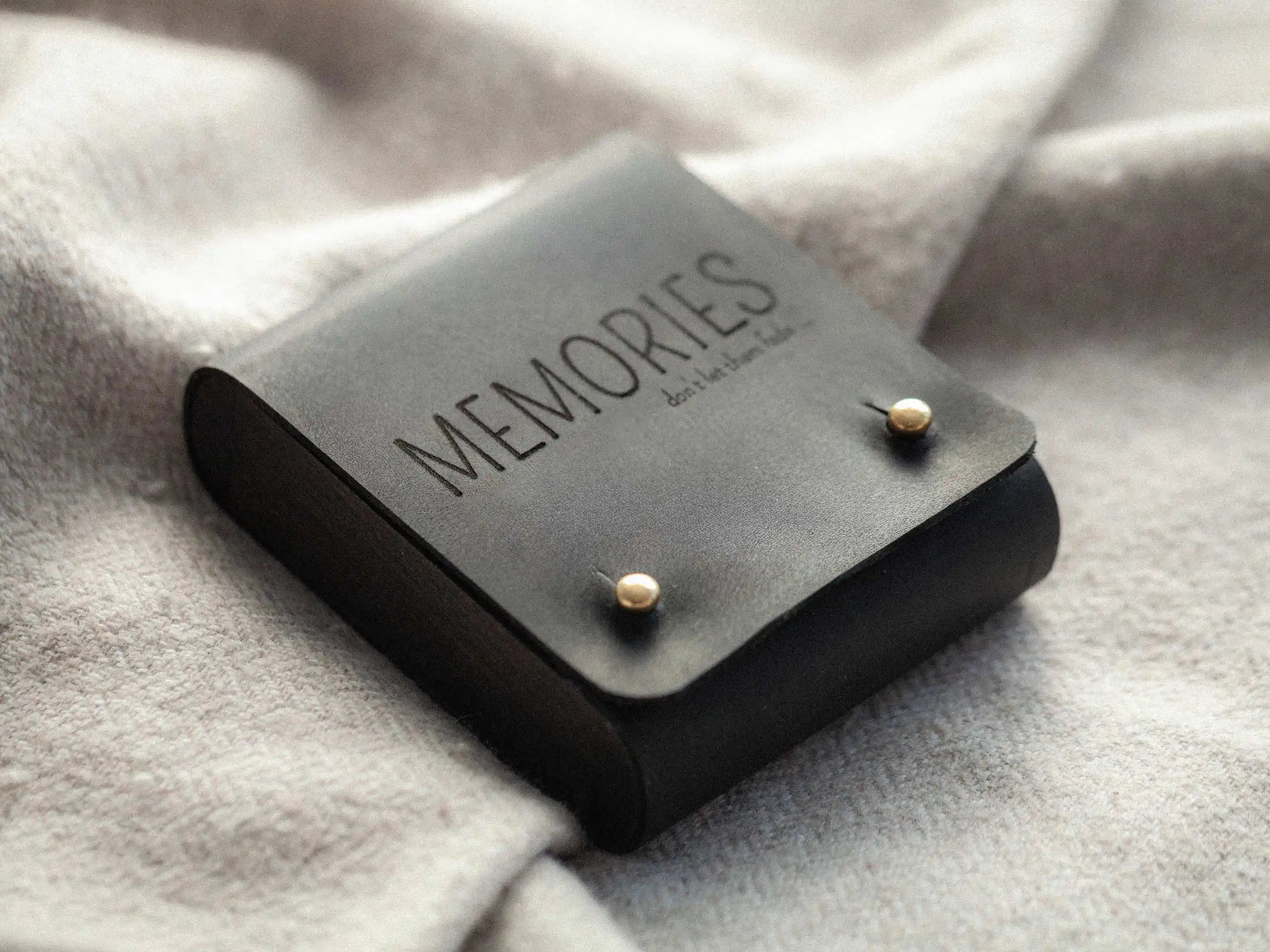 Black leather USB box with “MEMORIES” engraving, closed lifestyle on blanket