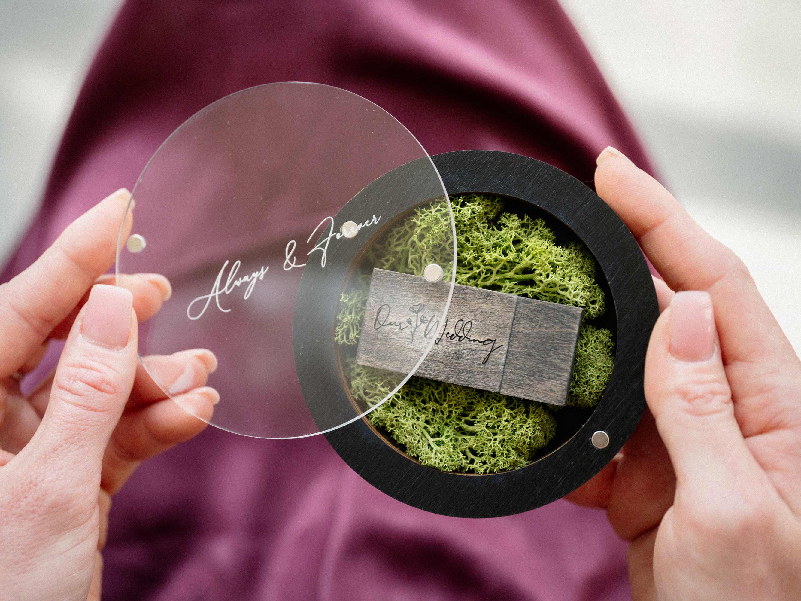 Open black wedding USB box with acrylic lid and wooden flash drive in hands