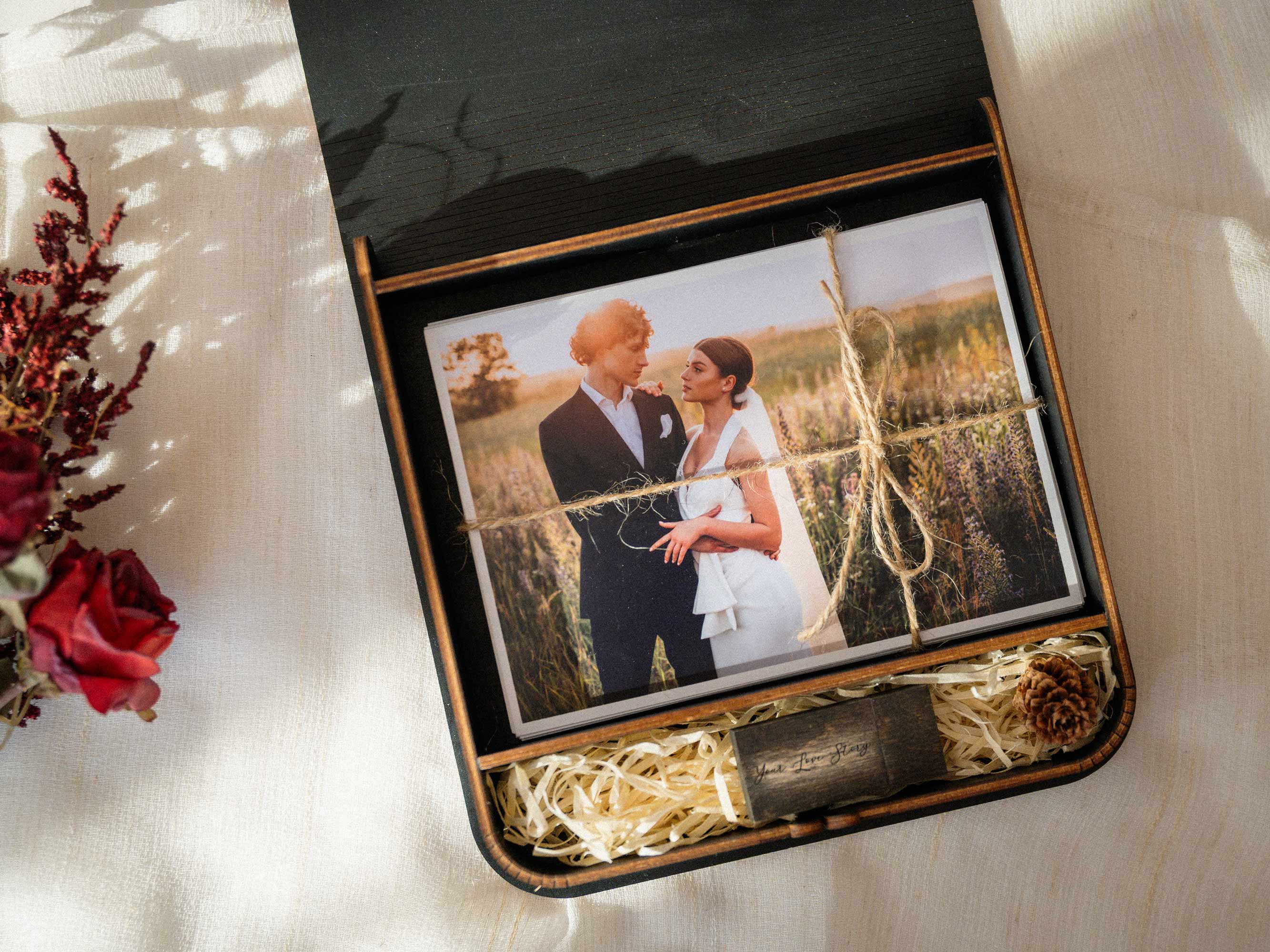 Open black wedding photo box with USB compartment and printed photos inside