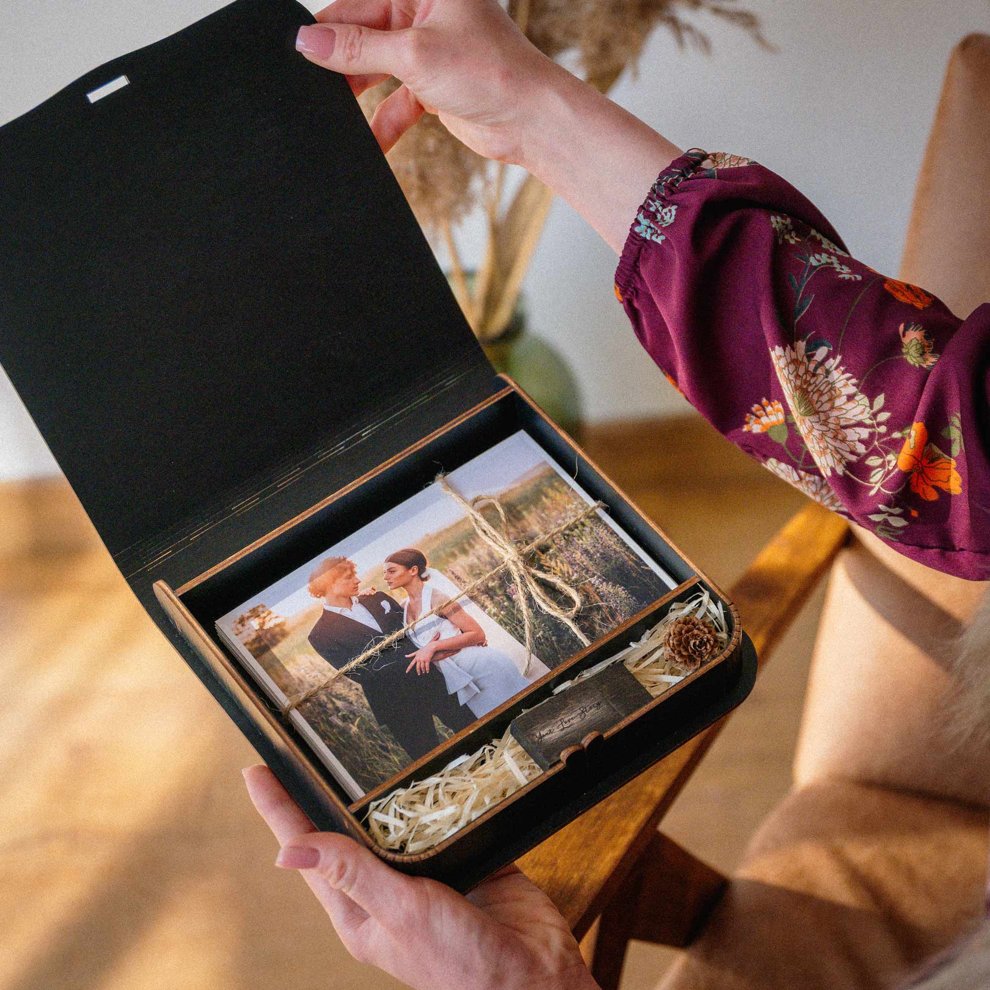Hands opening black wooden wedding photo box with USB and print storage