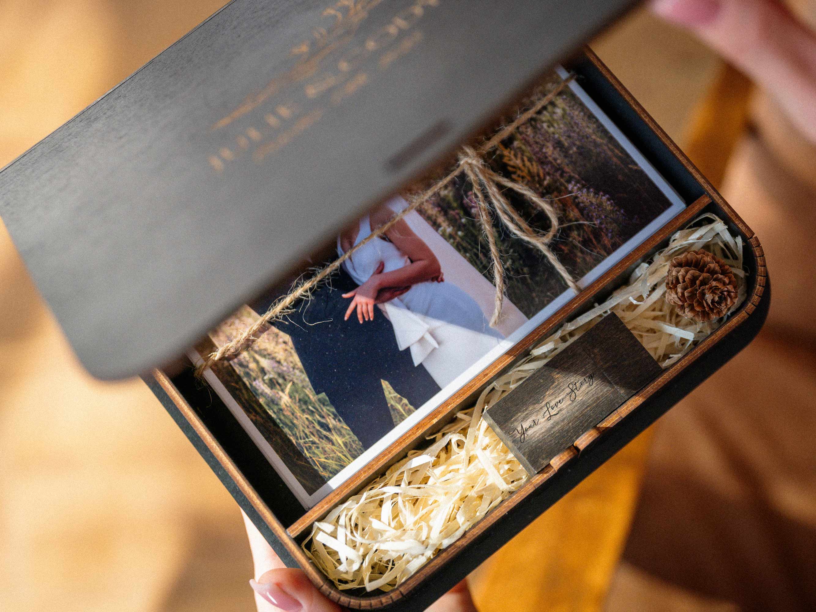 Partially open black photo box with wedding prints and USB compartment inside