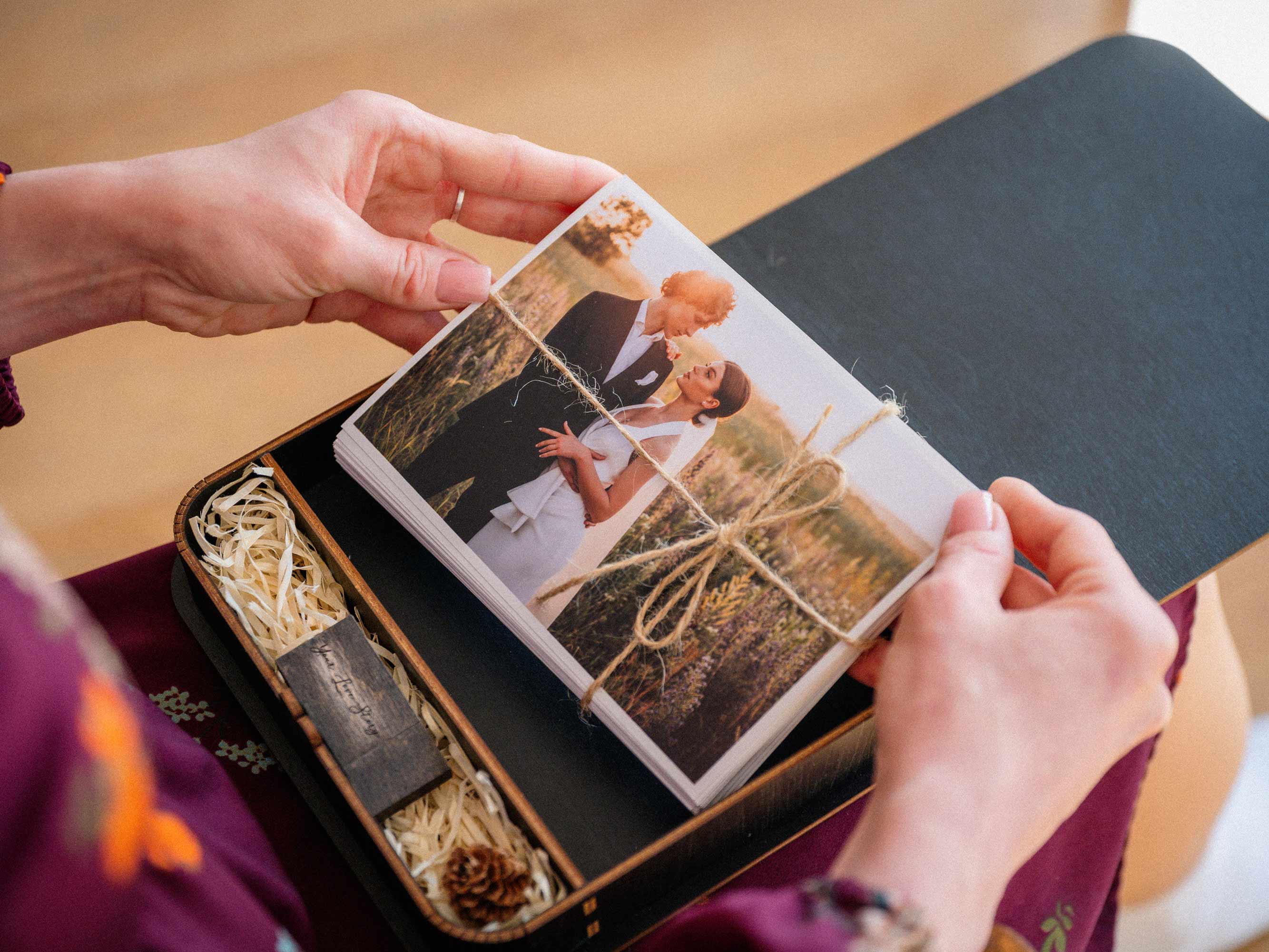Hands lifting wedding prints from black keepsake photo box with USB