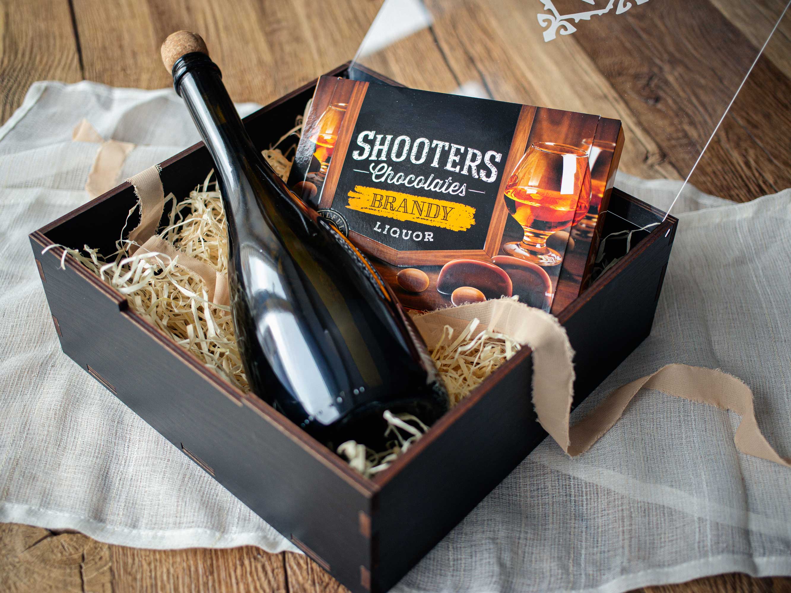 Black wooden gift box with acrylic lid styled with wine and chocolates, elegant personalized gift box example, contents not included