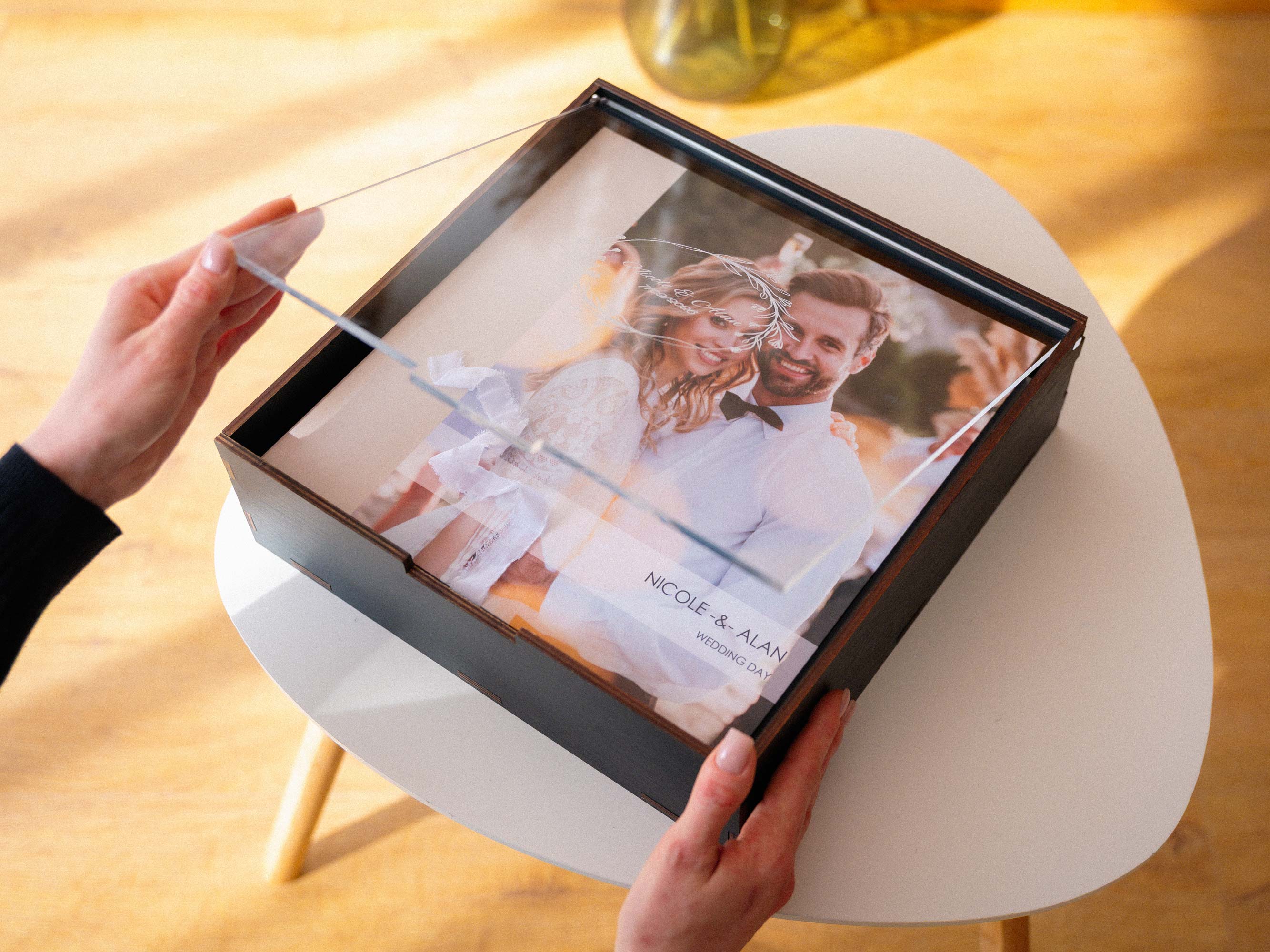 Black wooden wedding album box held in hands with acrylic lid
