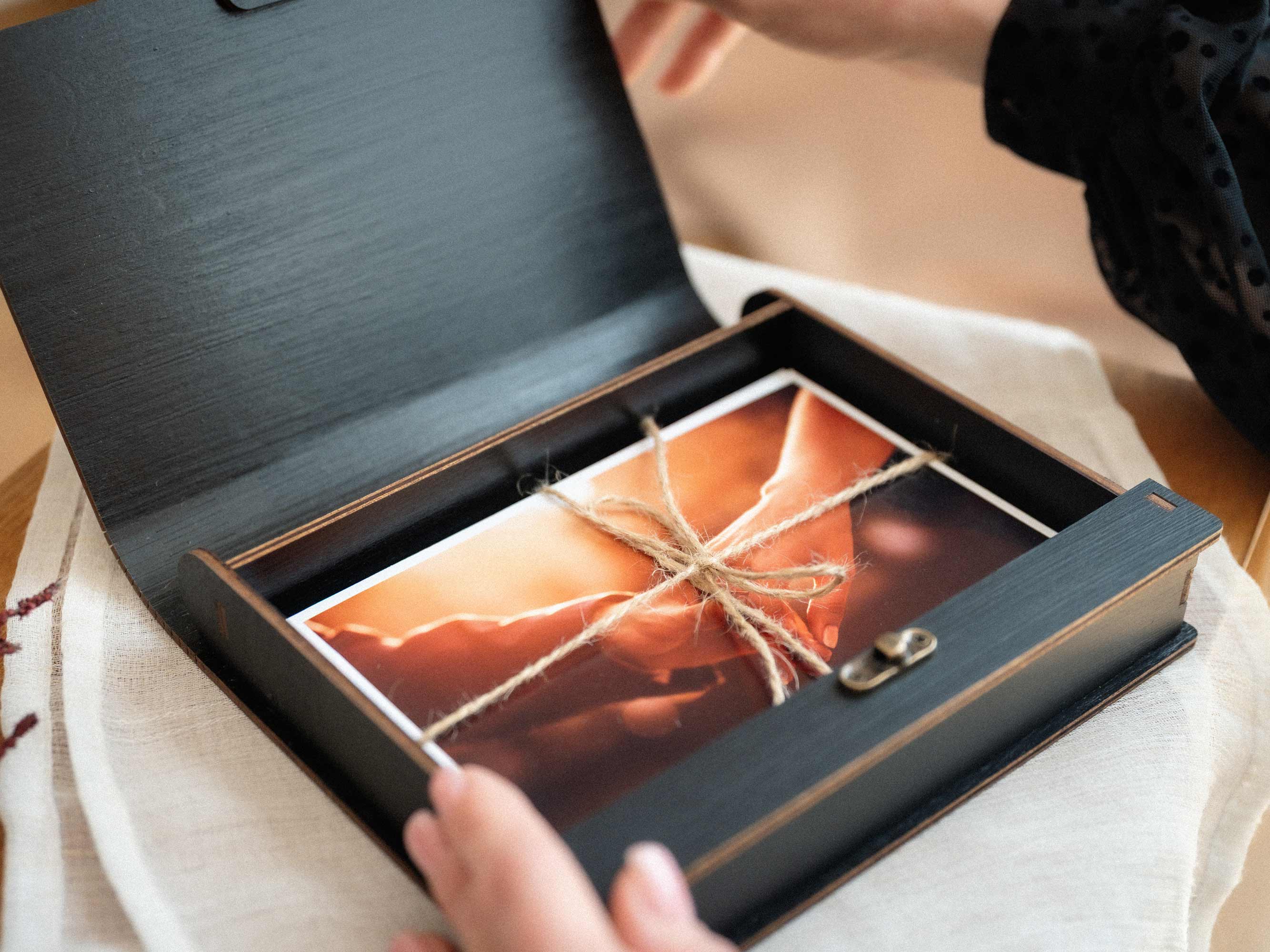 Black wooden photo box opening to reveal wedding prints