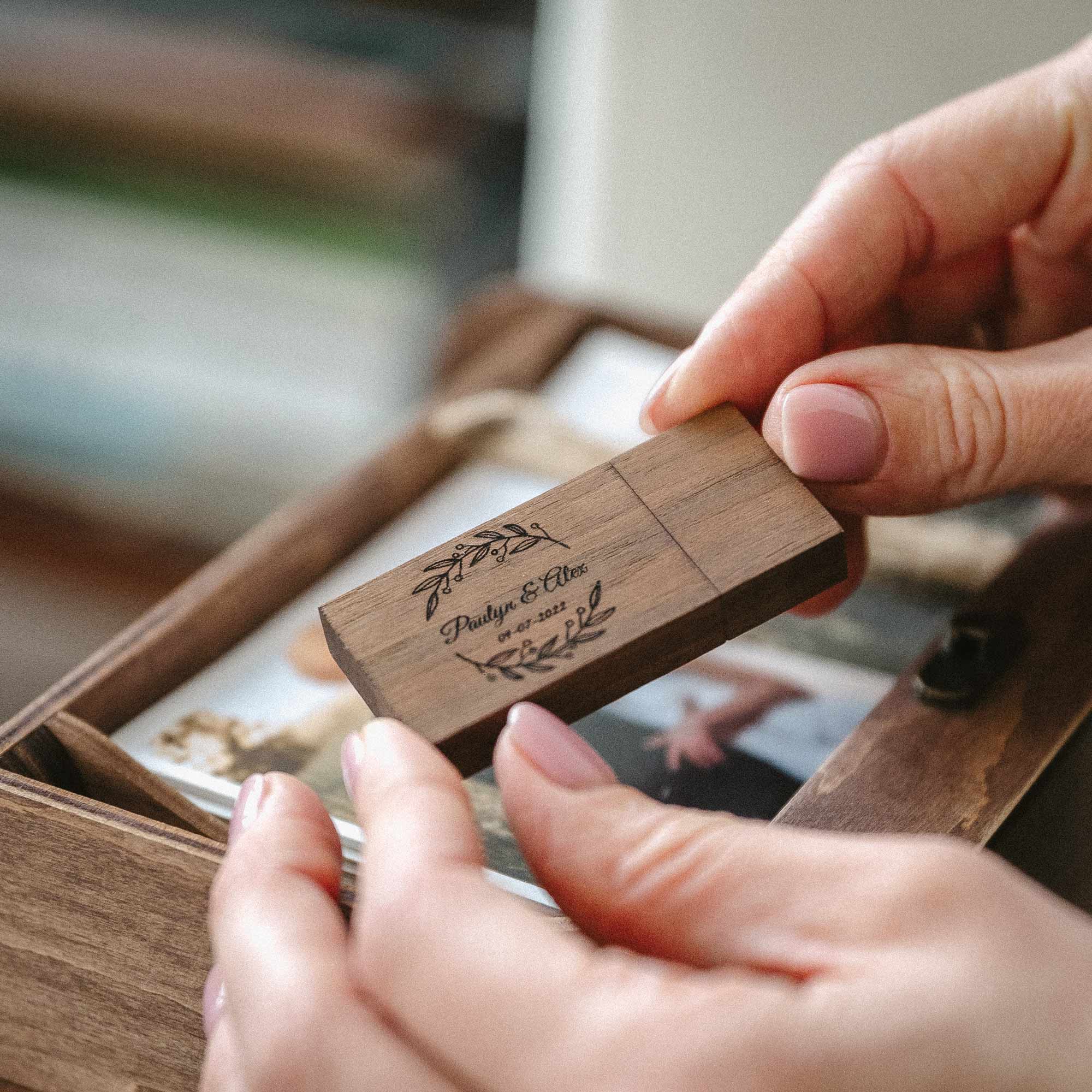 Hands placing engraved wooden USB flash drive into the slot inside walnut photo box