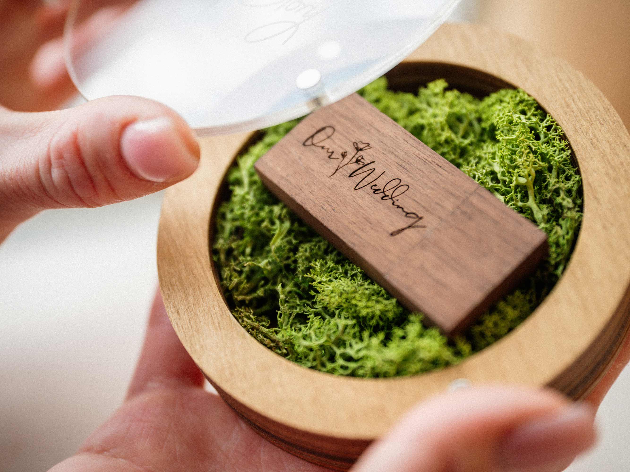 Gold Oak USB box with open acrylic lid and wooden flash drive on green moss