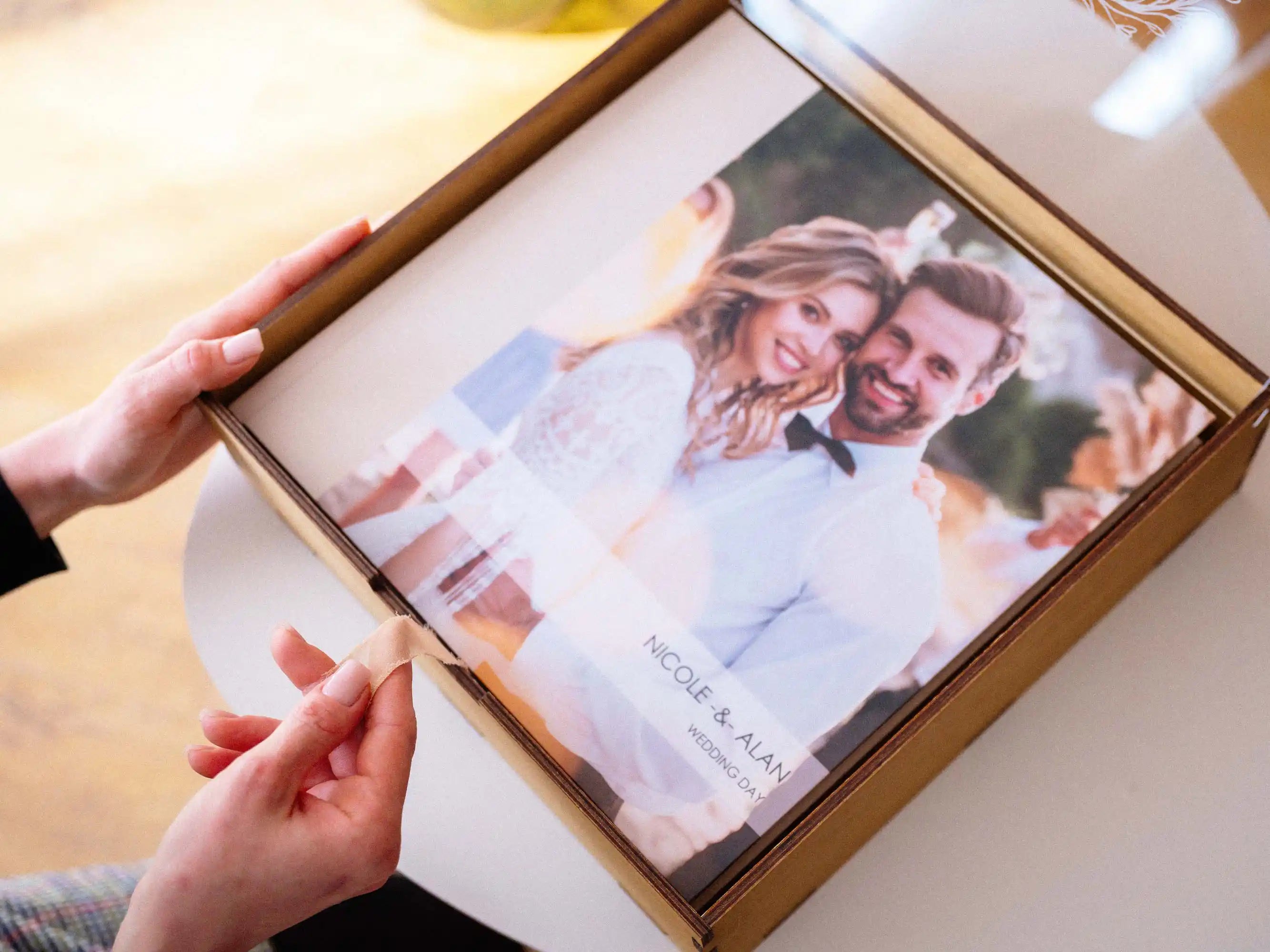 Gold Oak wedding album box held in hands with a 12x12 wedding album inside