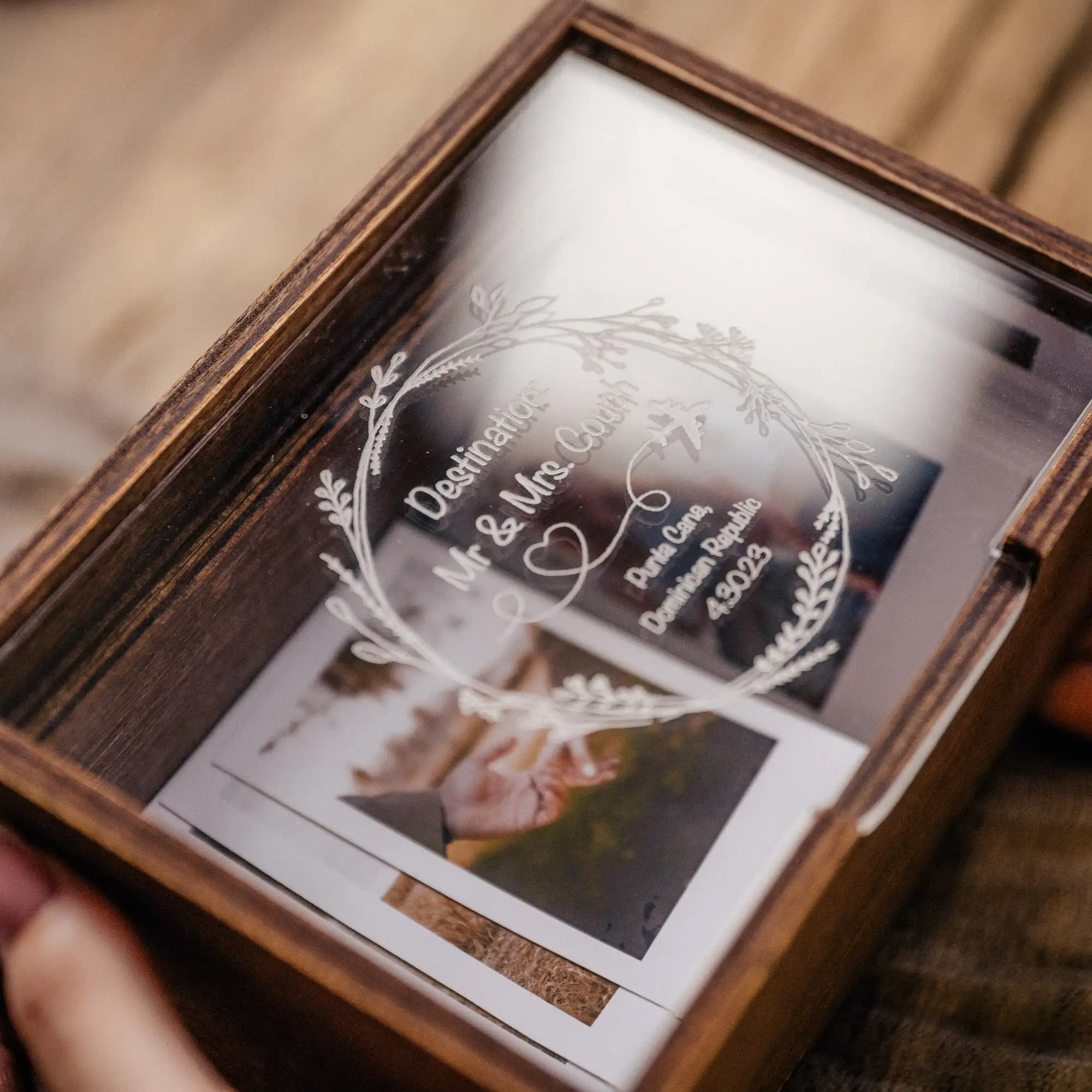 Close-up of a walnut Instax Mini photo box with acrylic lid and prints inside