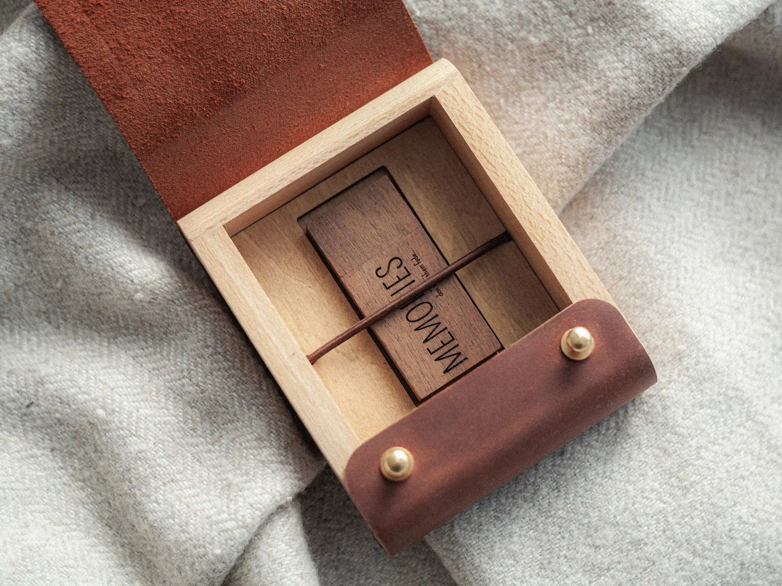 Open leather and wood USB box with wooden USB drive secured by elastic strap