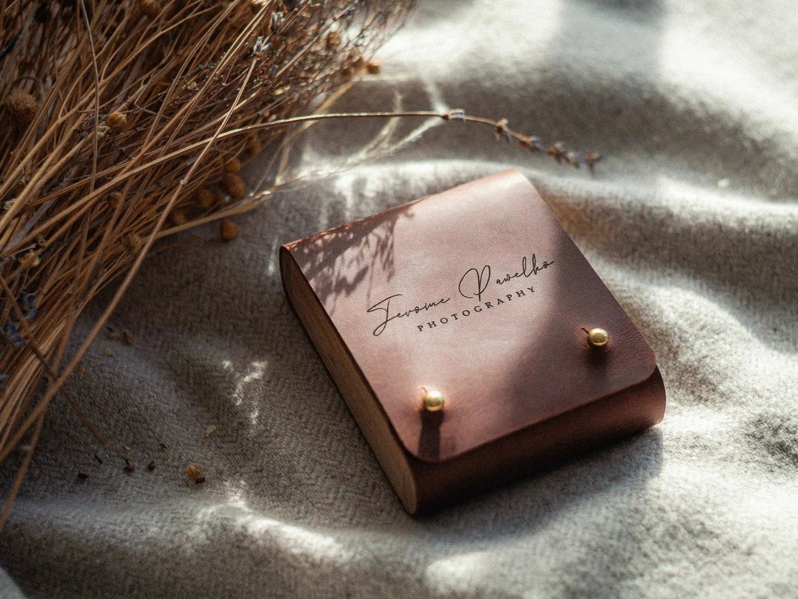 Cognac leather USB box with engraved logo, styled with dried flowers on blanket