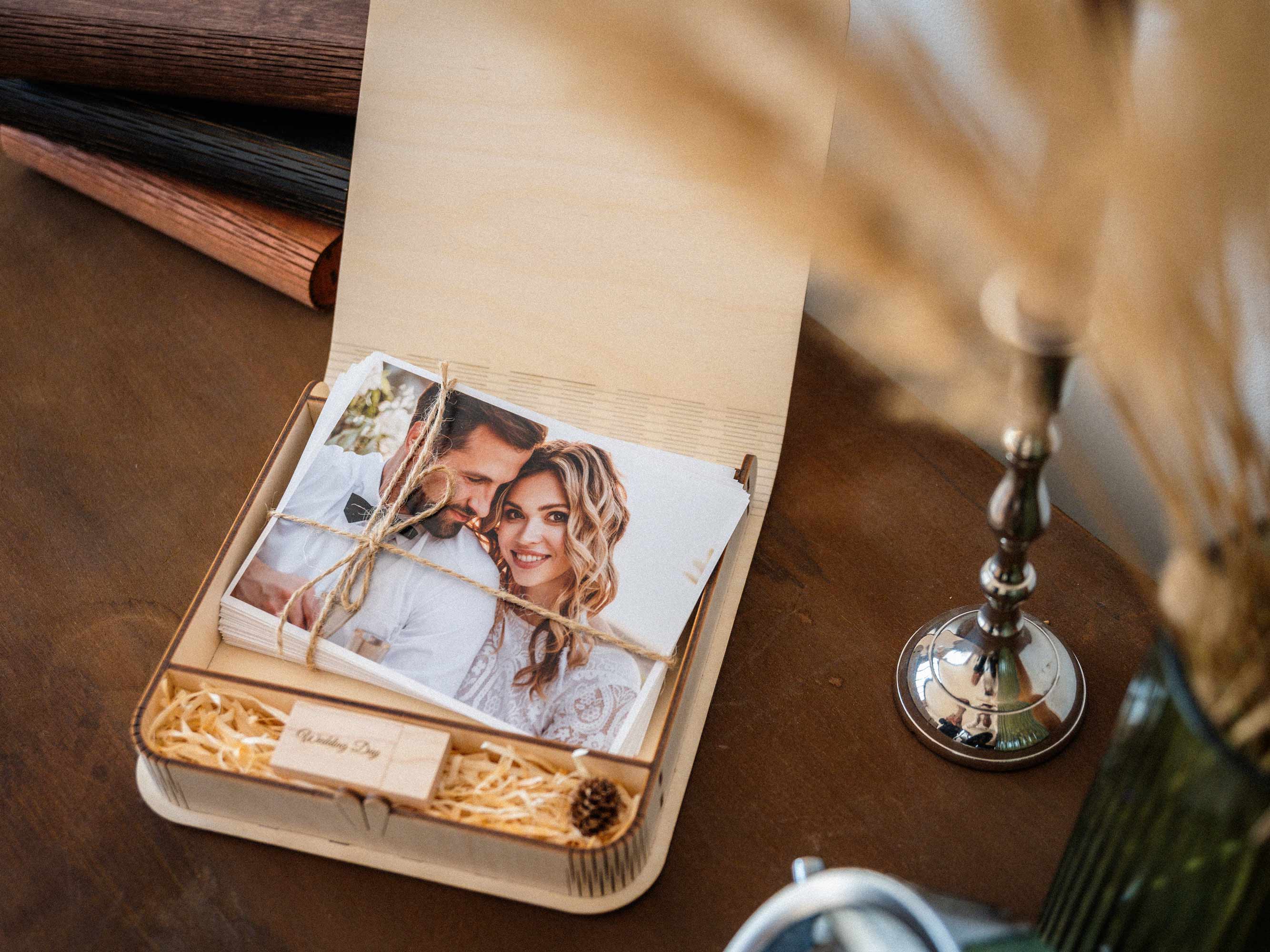 Open maple wedding photo box with USB and wedding prints on a styled table