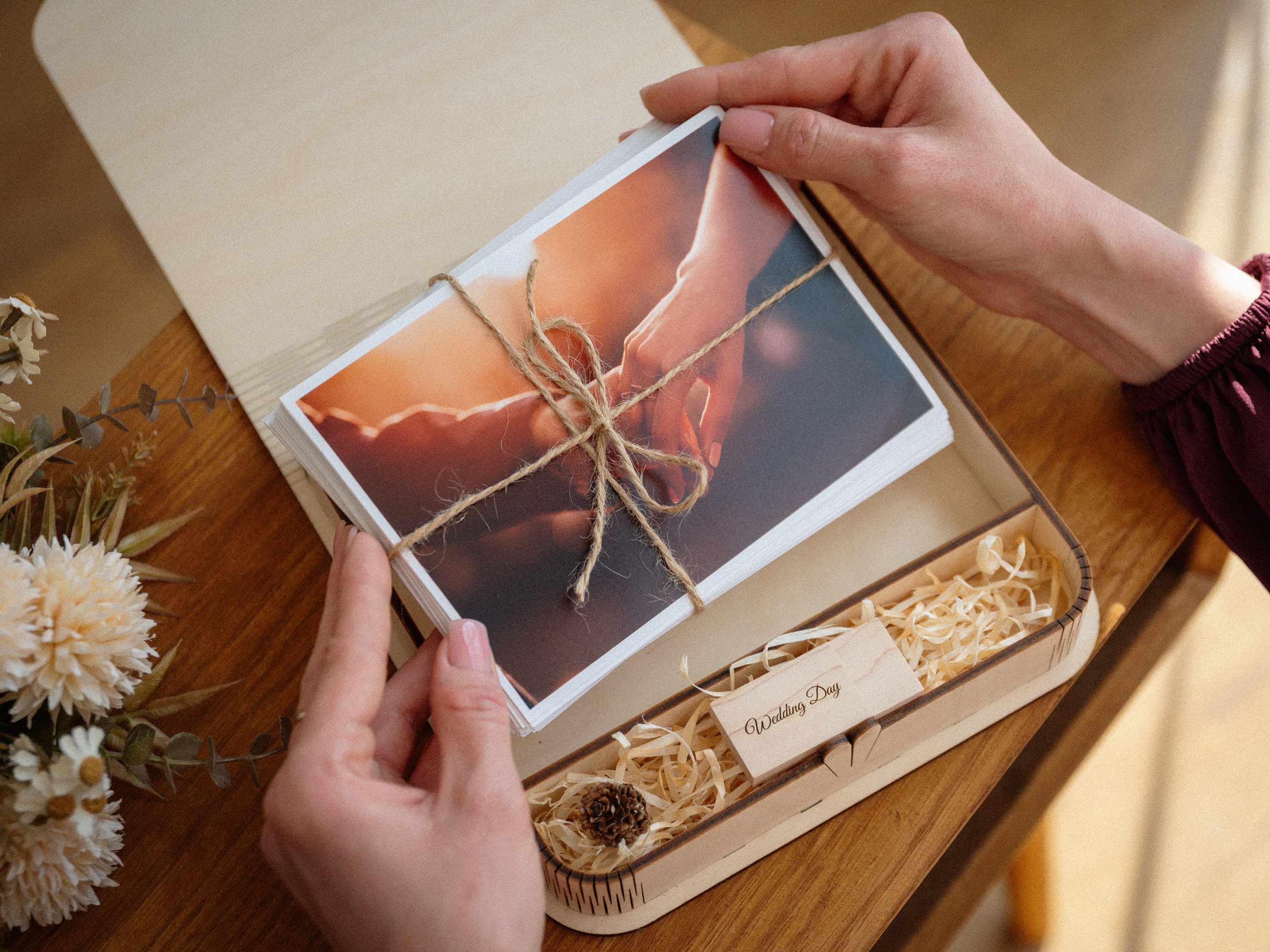 Open maple wedding photo box with USB and printed photos being lifted out