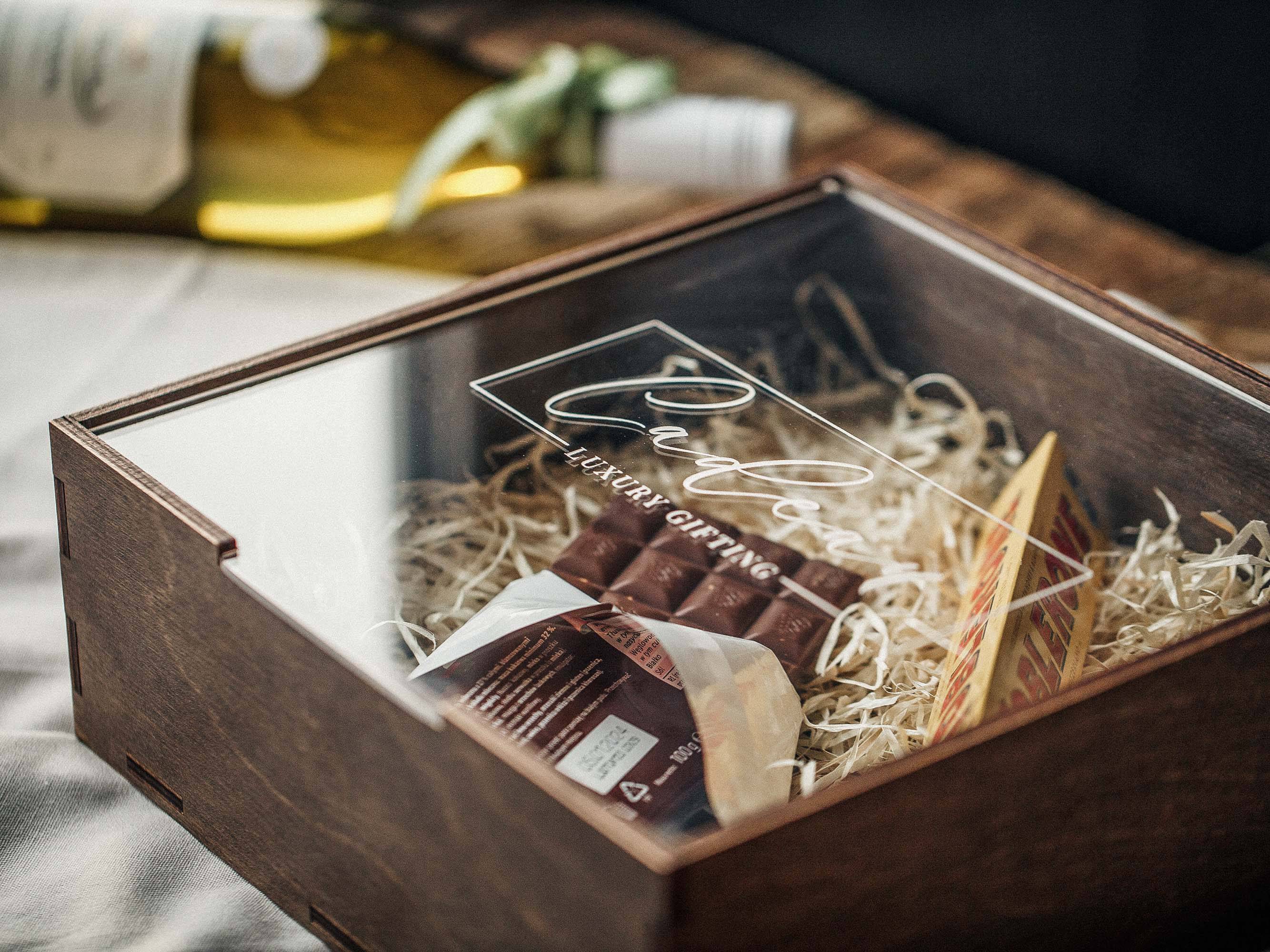 Walnut gift box with acrylic lid filled with wine, chocolate, and gift filler