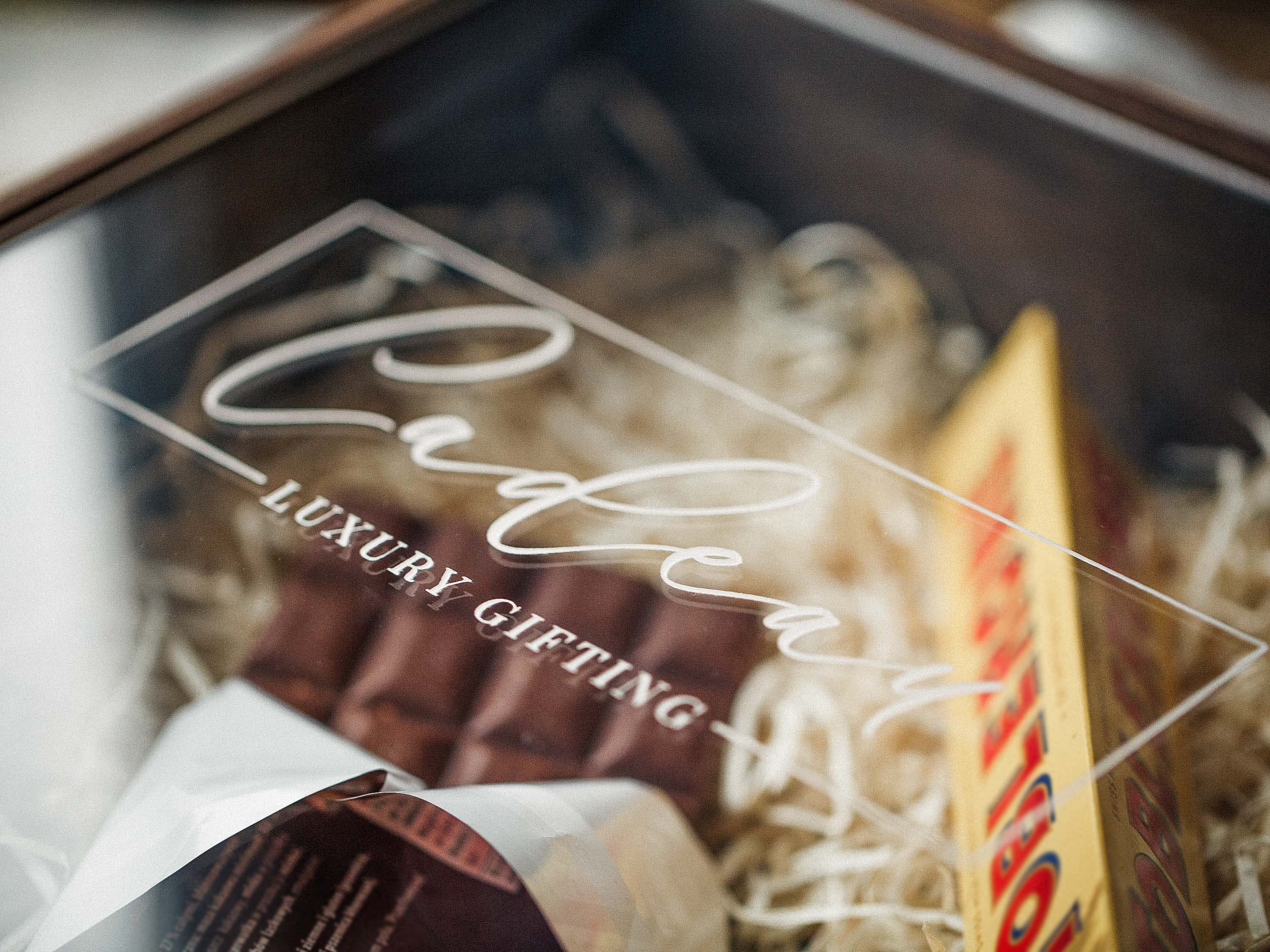 Close-up of acrylic lid engraving on walnut wooden gift box with wine gift inside