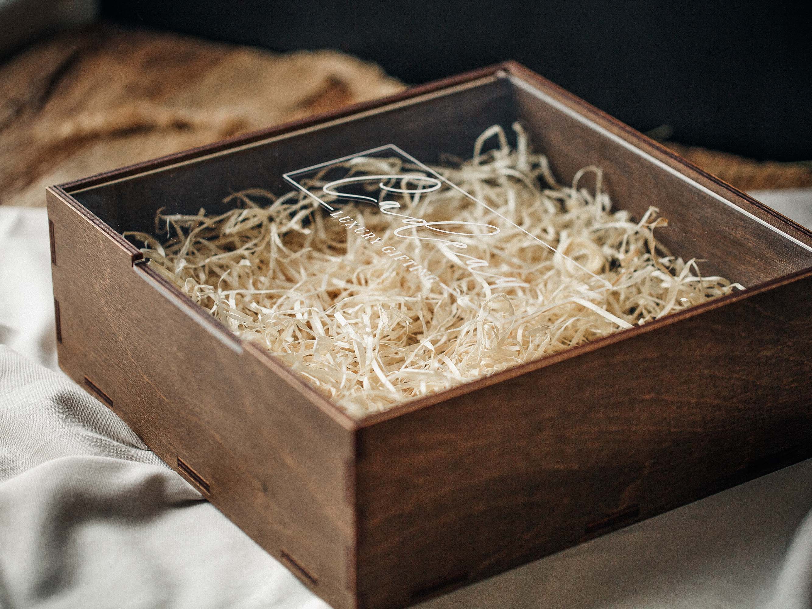 Empty walnut wooden gift box with acrylic lid and natural wood shavings inside