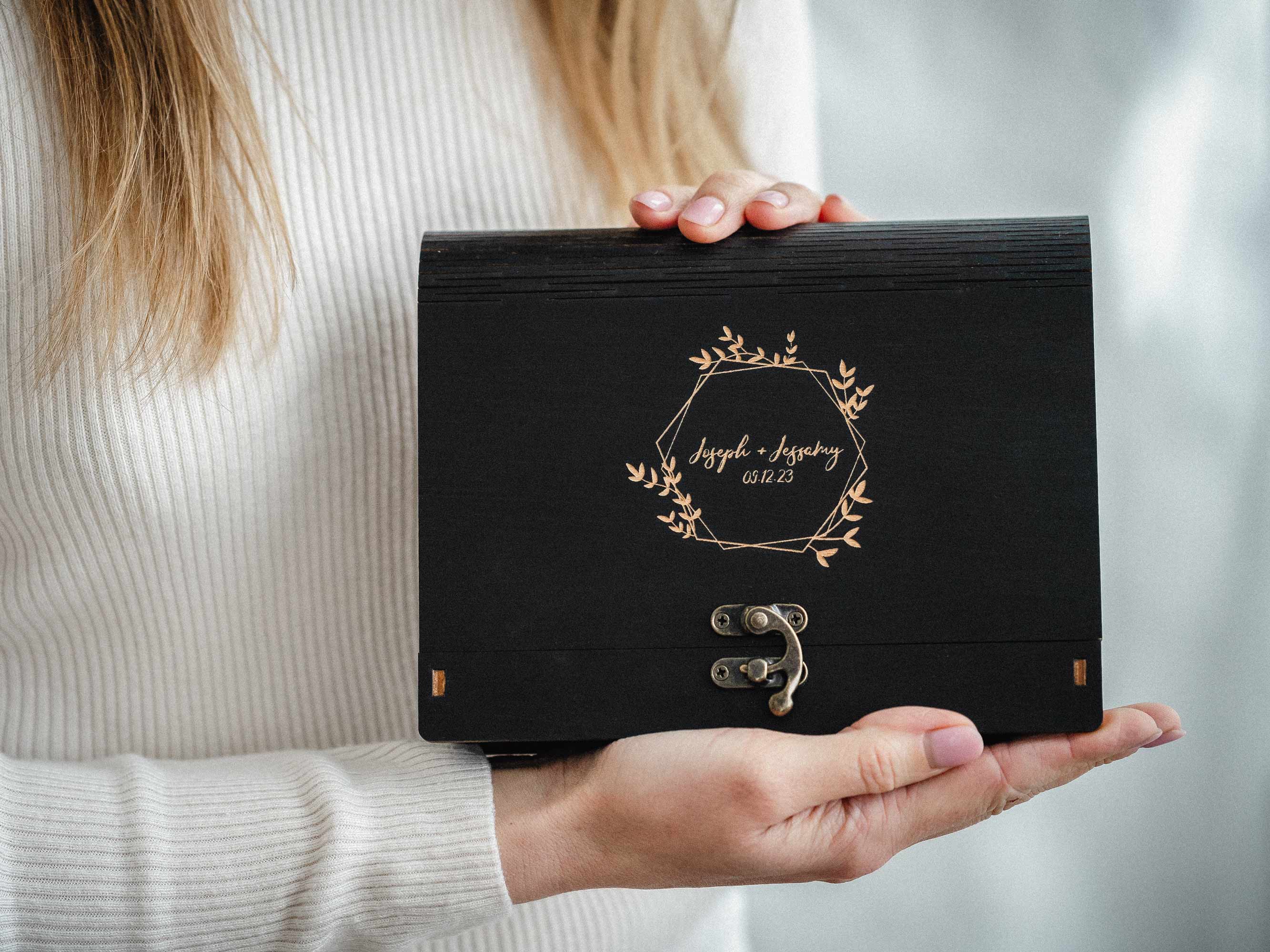 Woman holding personalized black wooden photo box with engraved lid, centered product shot
