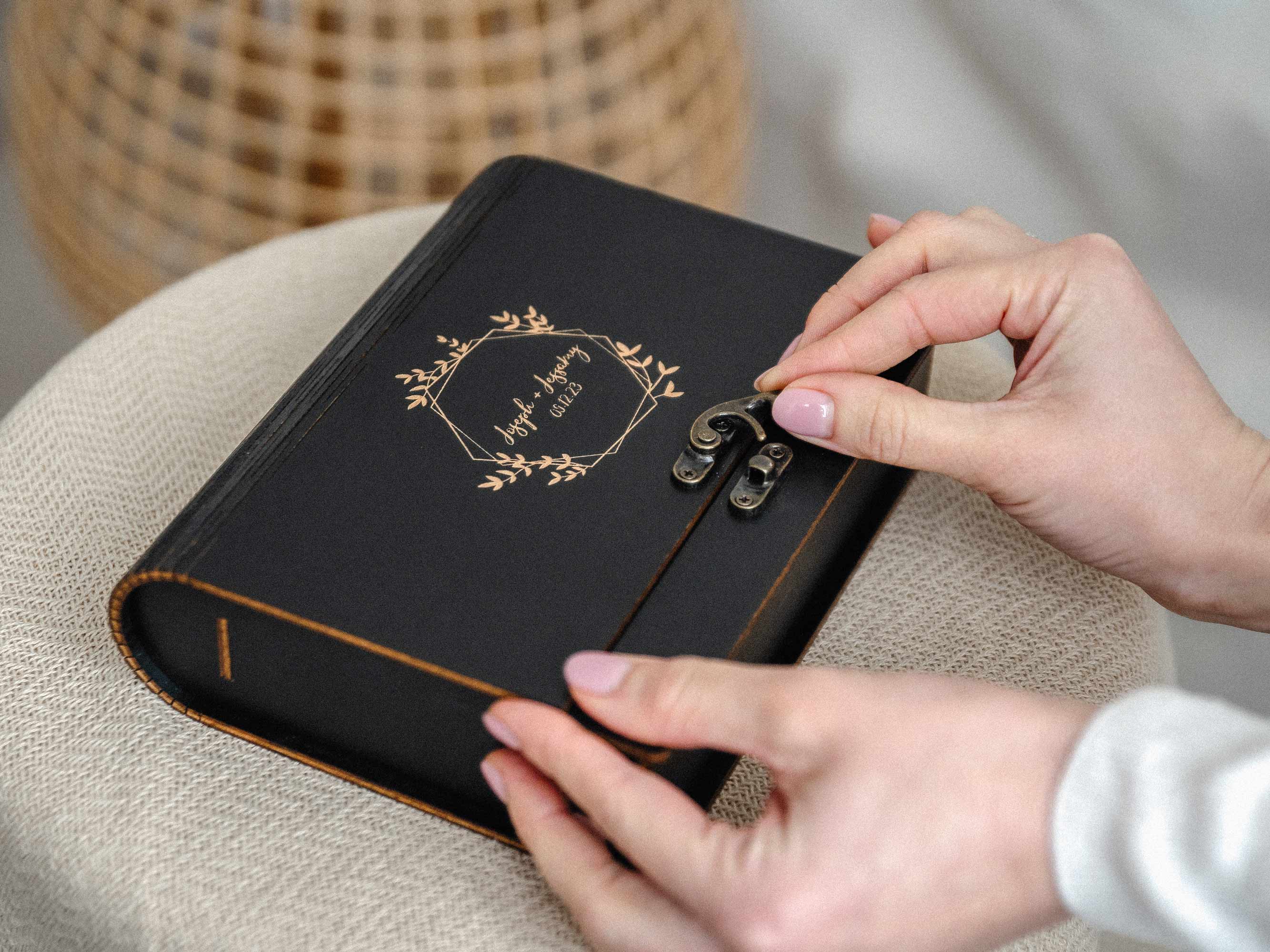 Hands closing black wooden photo box with metal latch, gift-ready photographer client experience