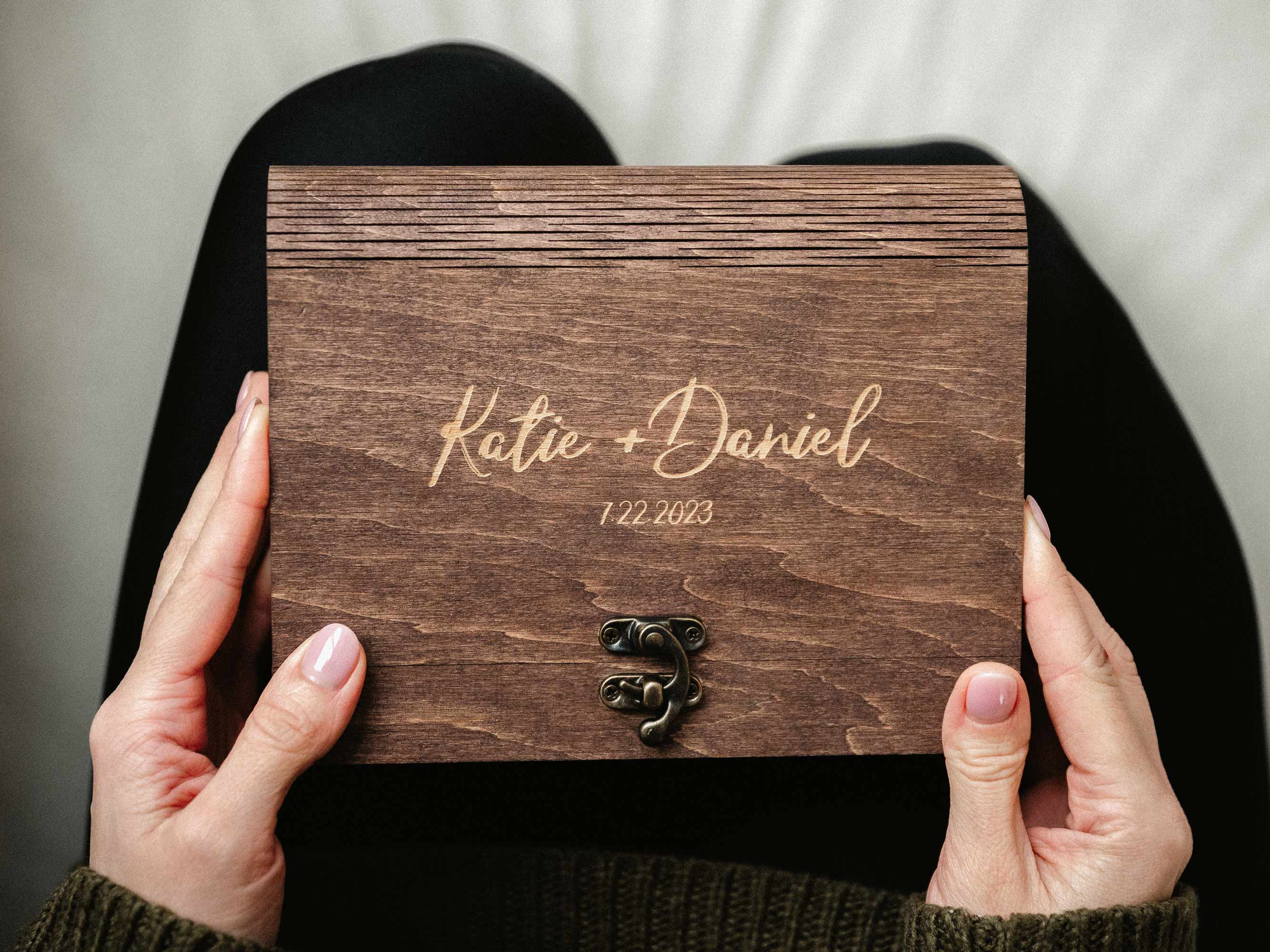 Wedding photo stack held above open walnut box, unboxing moment