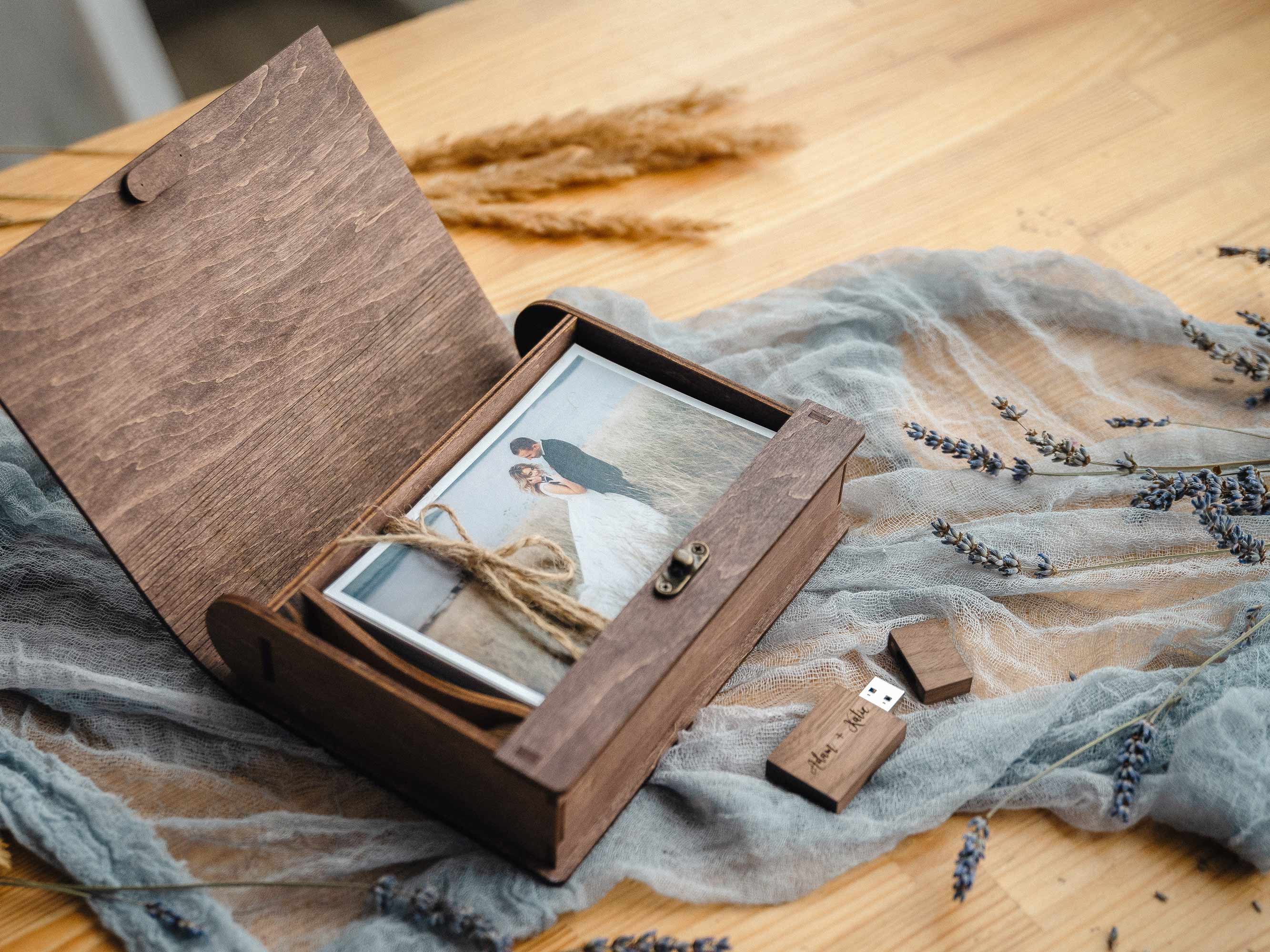 Open walnut classic photo box with prints, twine and wooden USB on linen