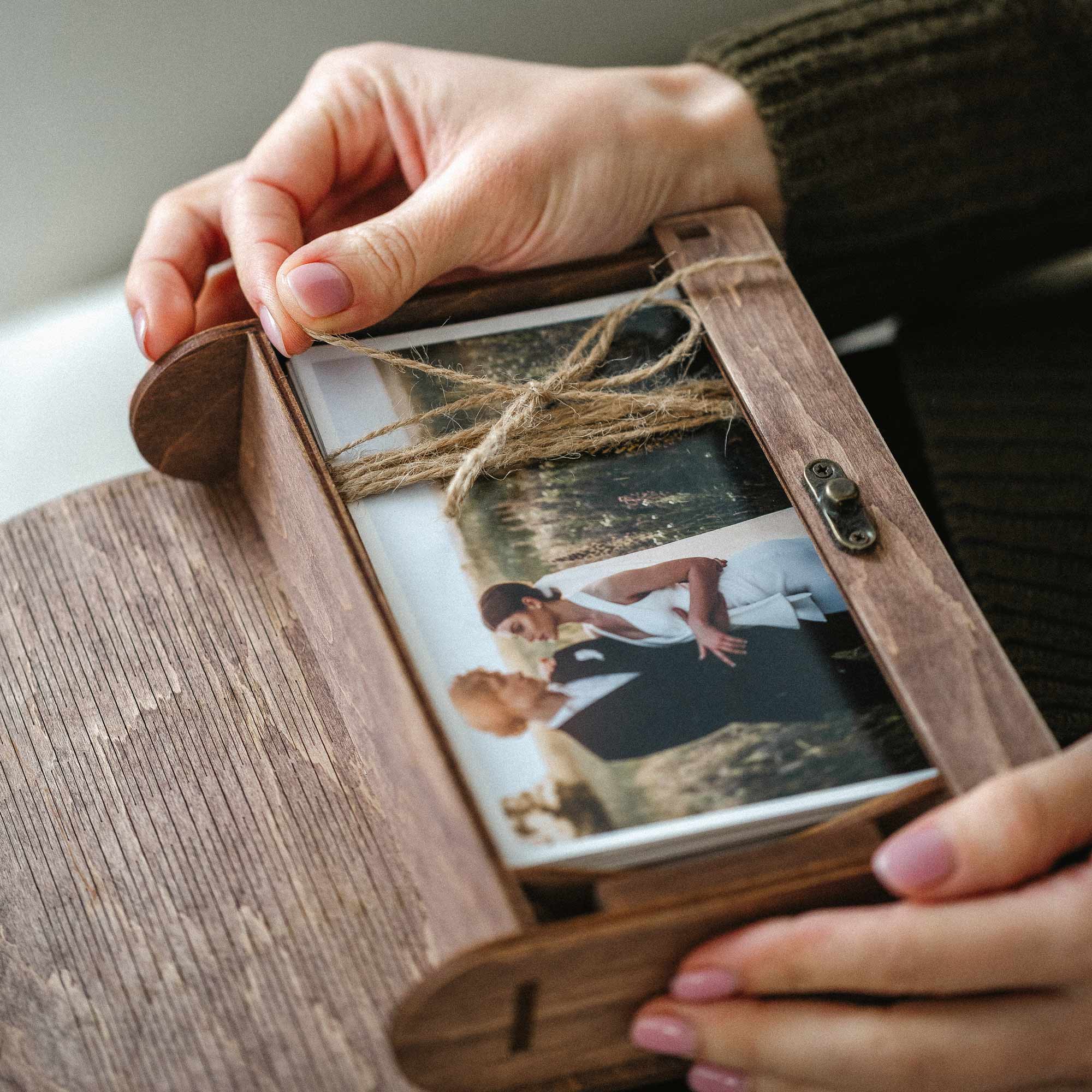 Closed walnut wooden photo box flatlay on linen with wedding prints