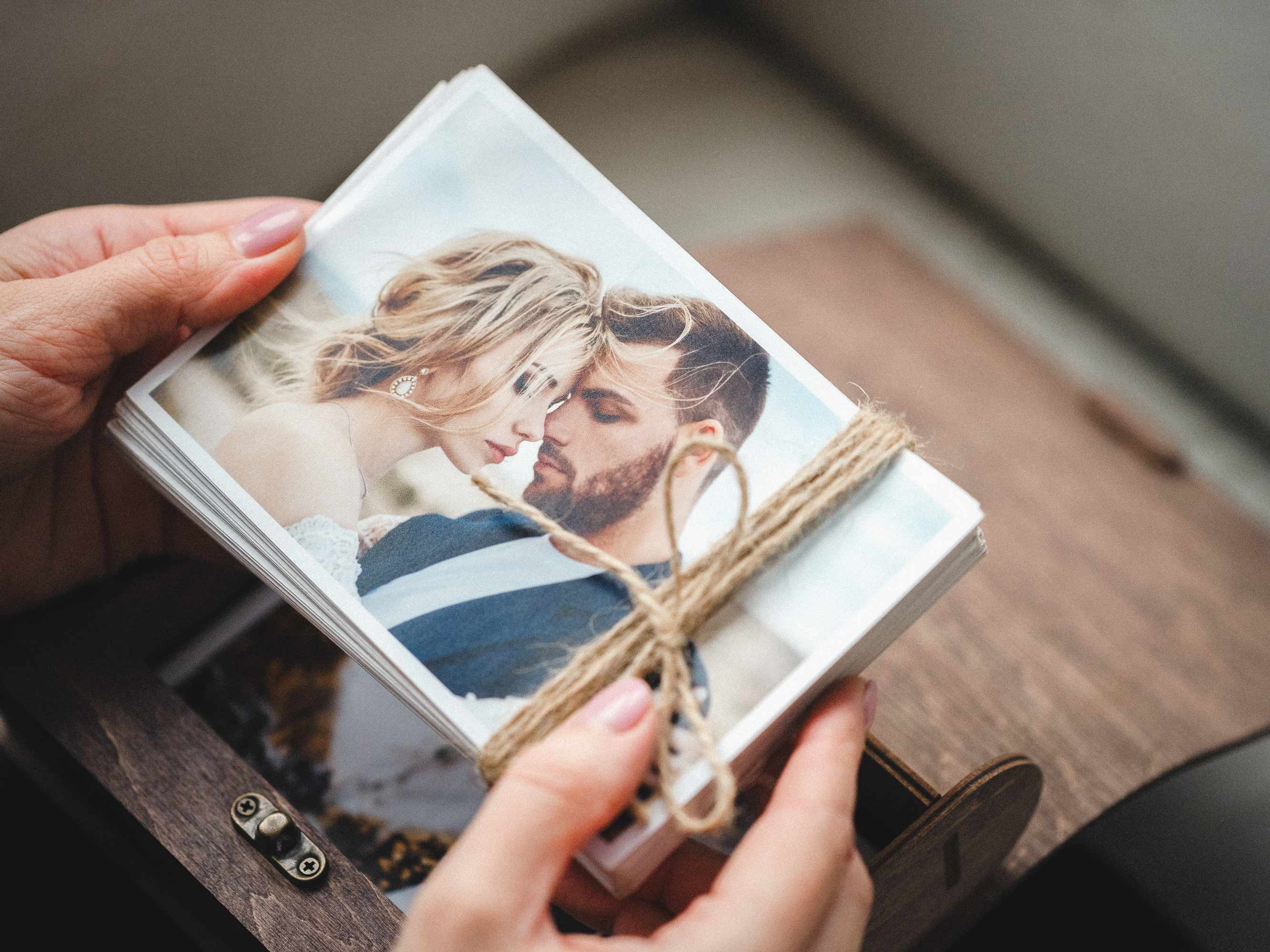 Hands holding wedding prints above walnut classic photo box, client reveal