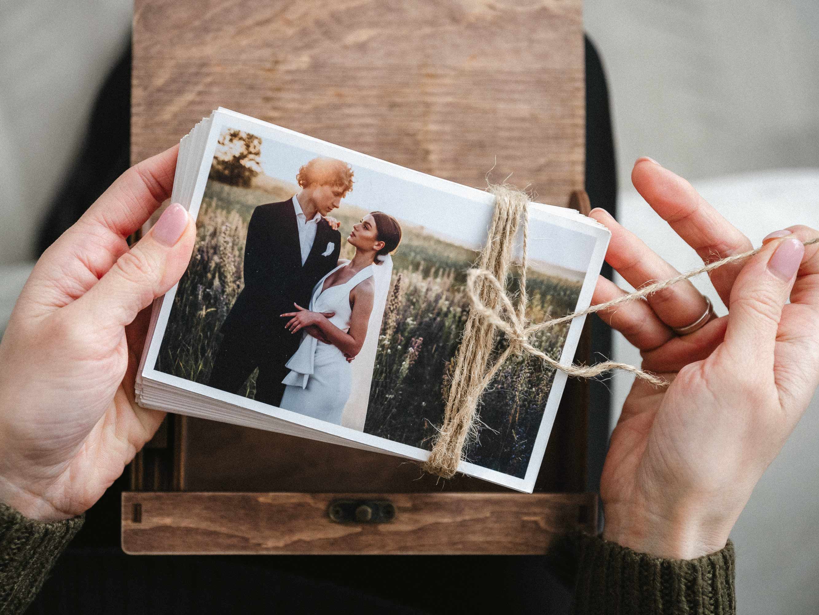 Hands holding closed walnut wooden photo box with engraved names