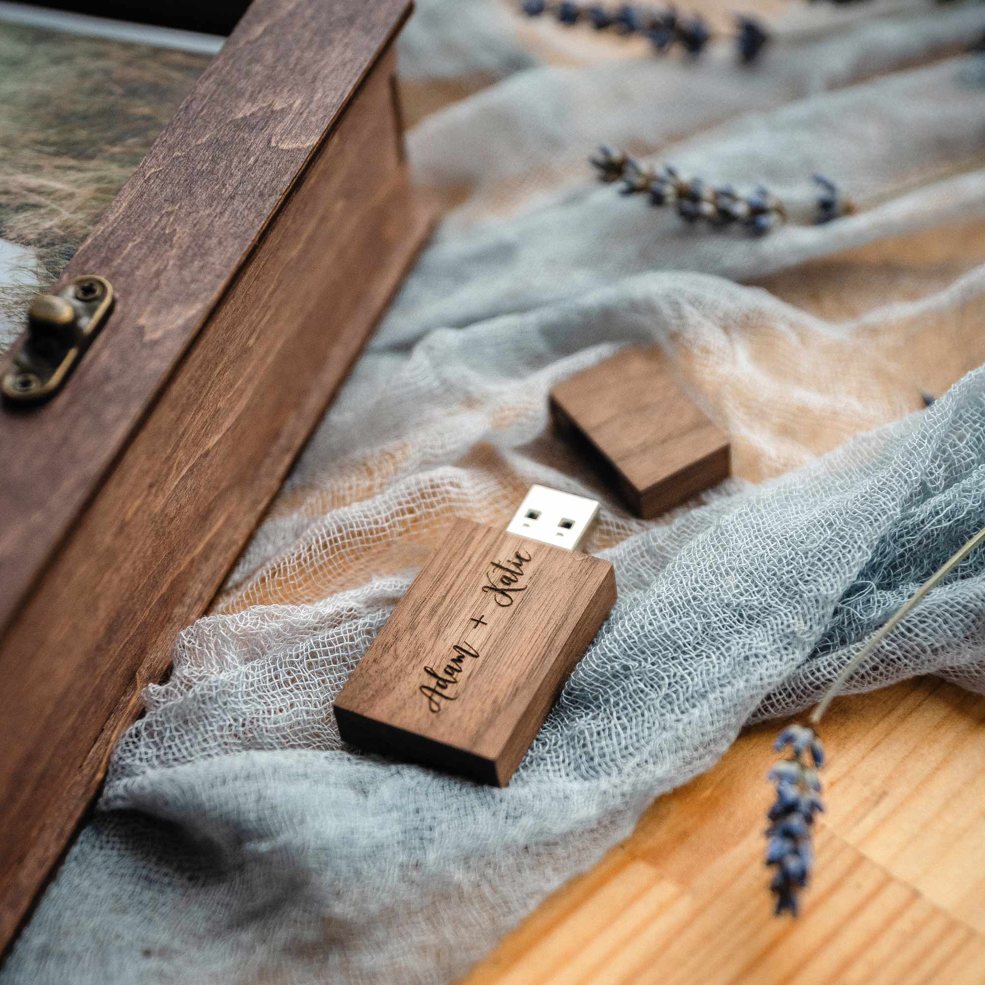 Hand placing engraved wooden USB into walnut box compartment on linen
