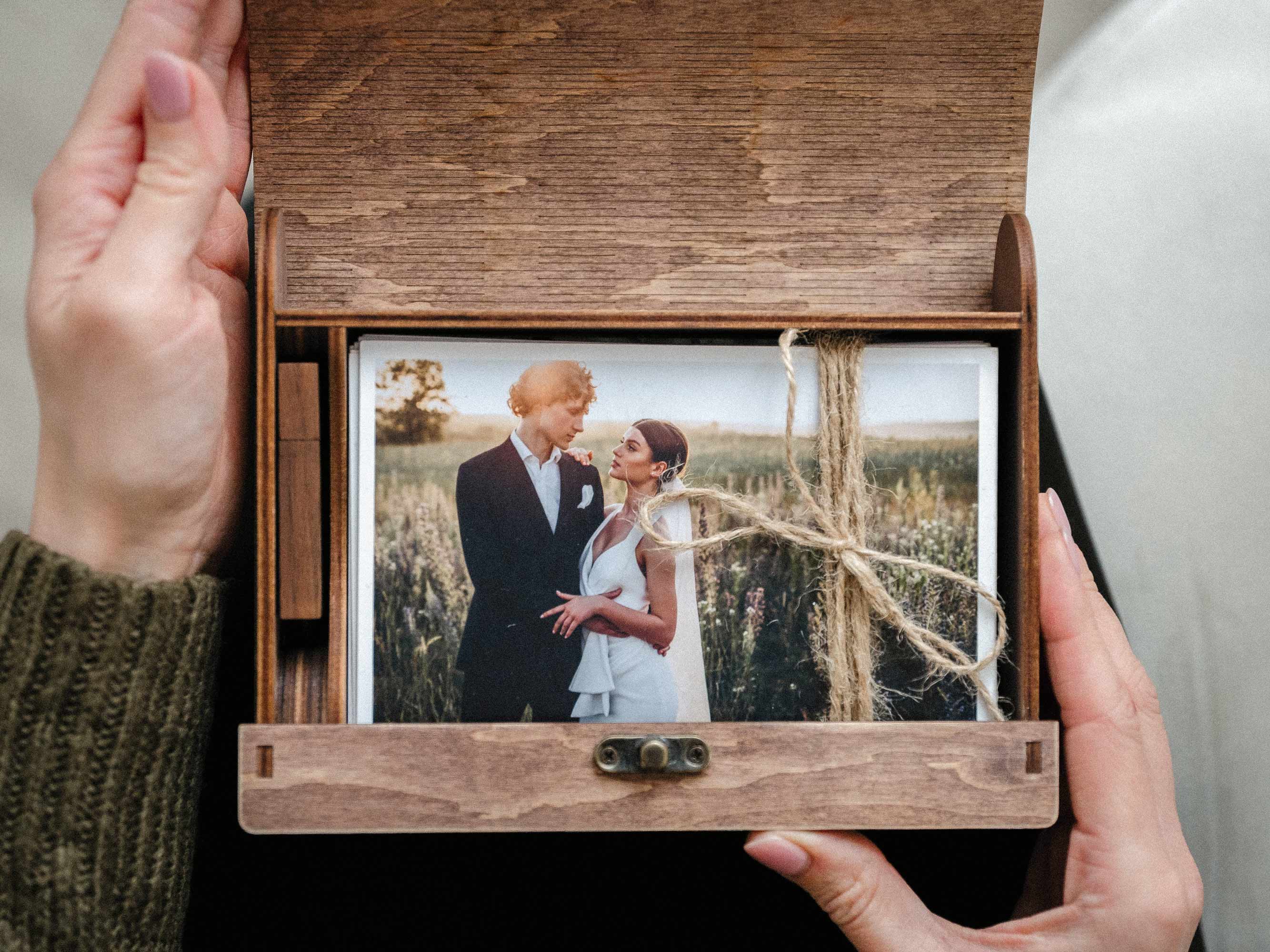 Open personalized walnut wedding photo box held in hands, showing printed photos inside