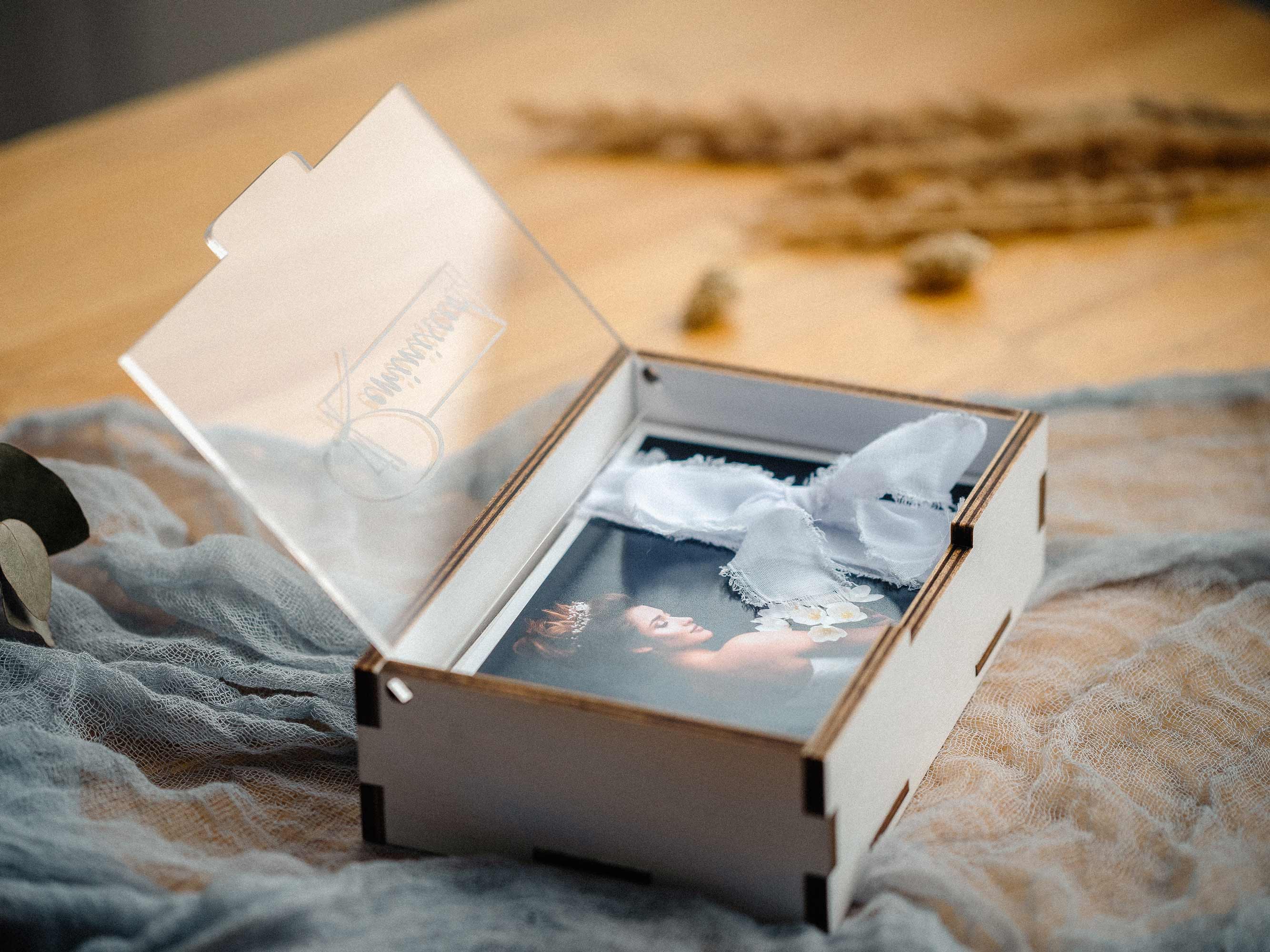 White wooden print box on fabric with engraved acrylic lid half open.