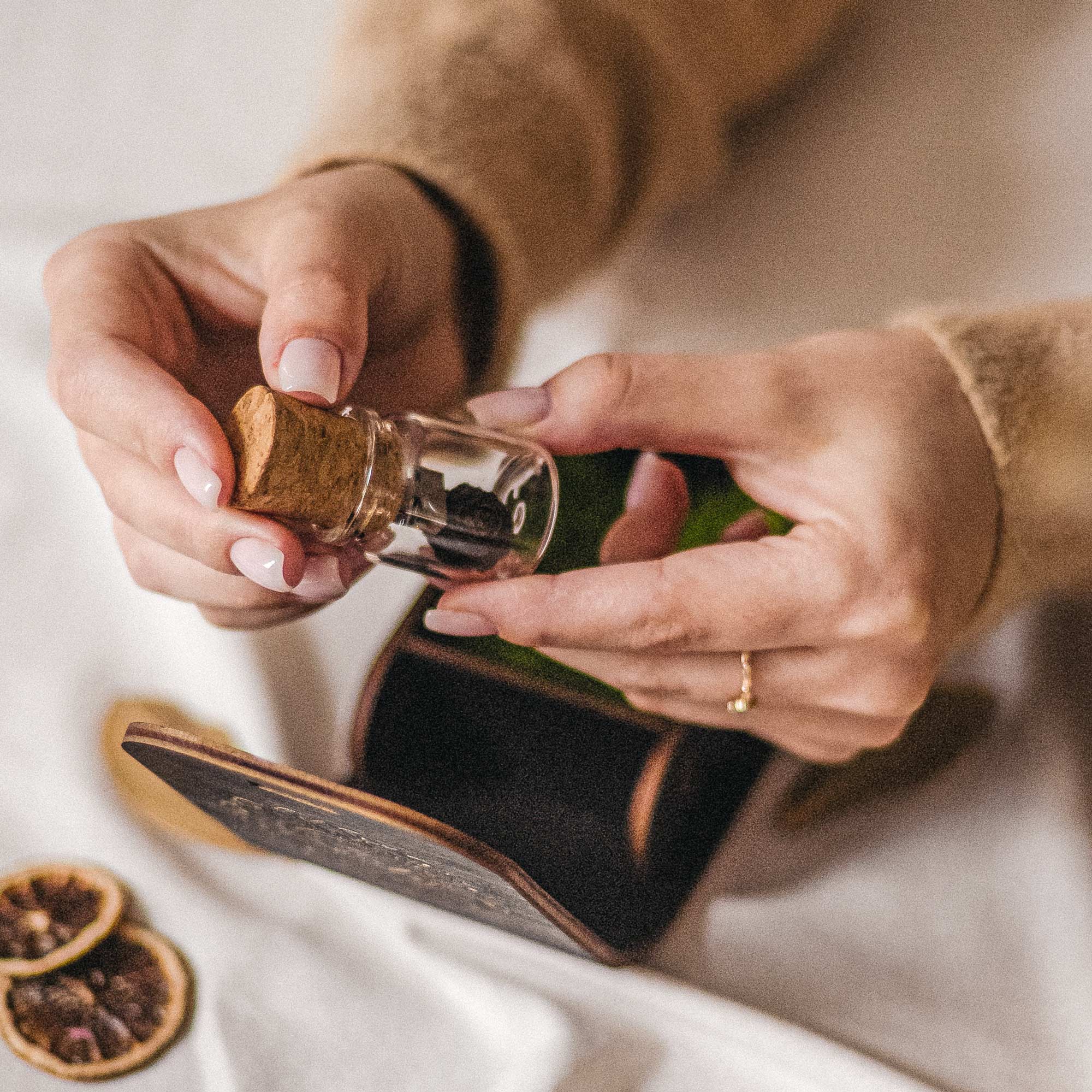 Hands holding Glass Jar USB with small natural pine cone beside open black box
