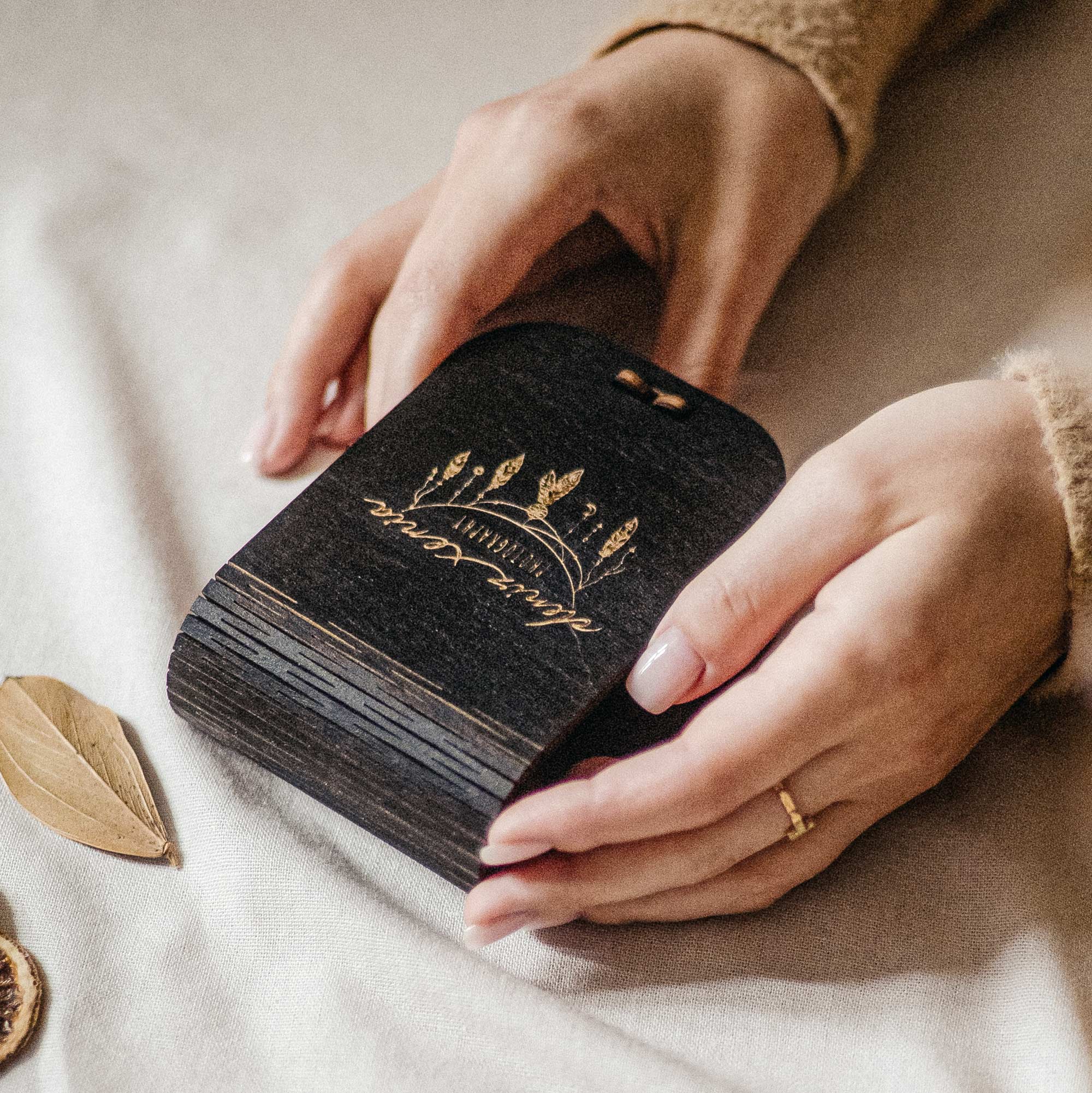 Closed black wooden USB box with personalized engraving held in hands