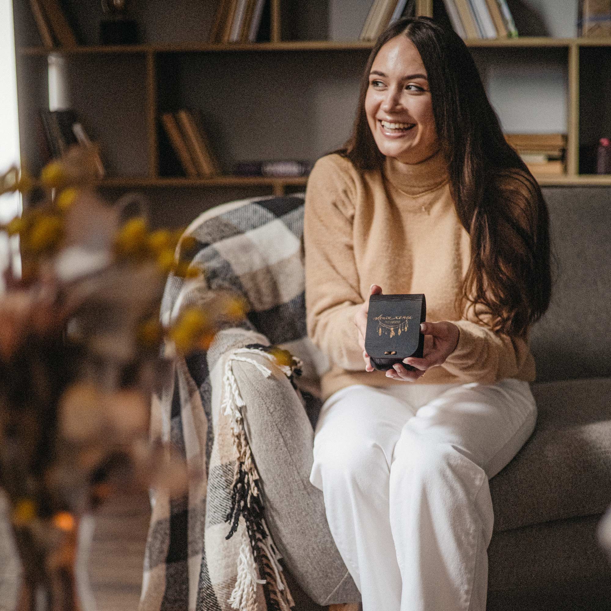 Woman holding black engraved USB box in a cozy living room setting