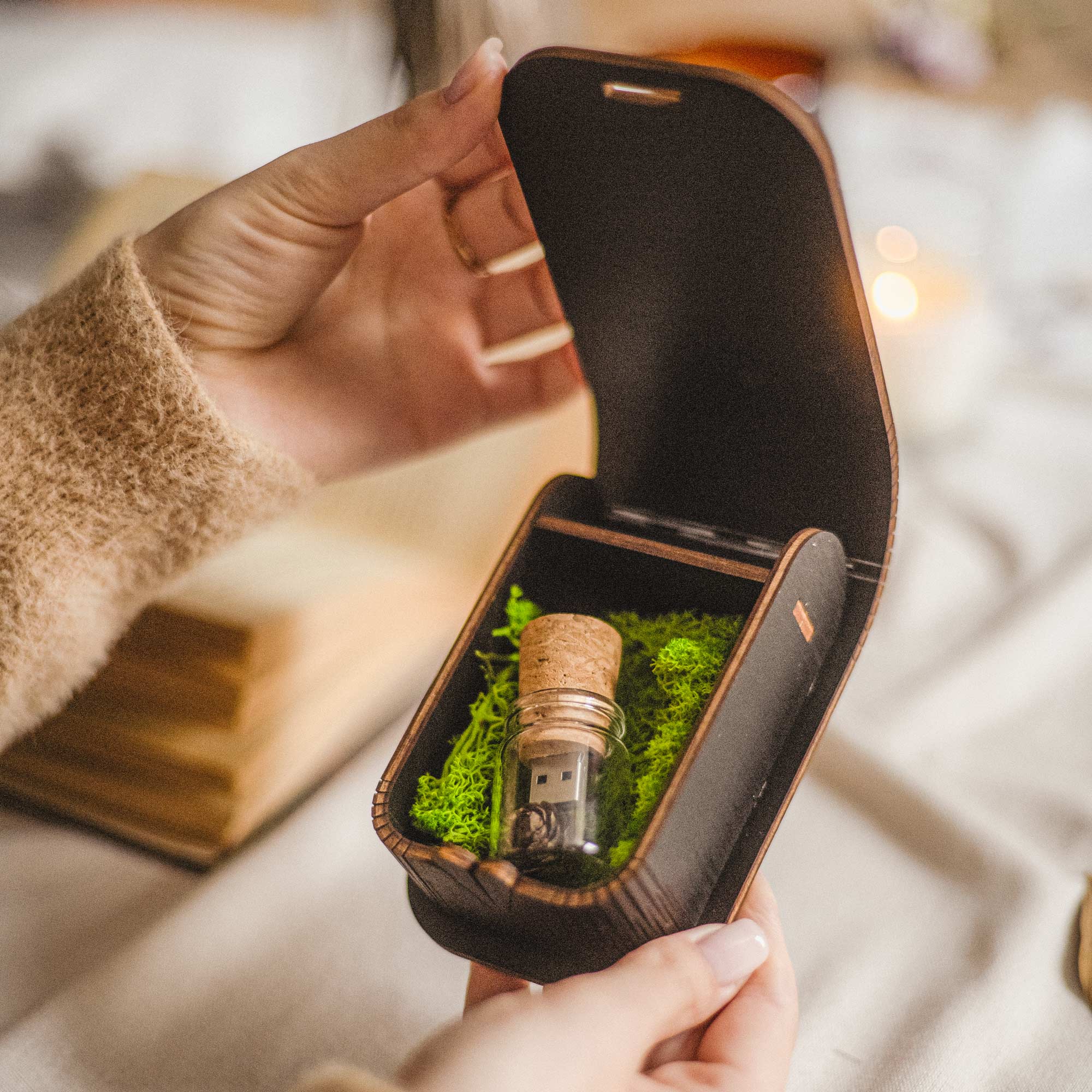 Black wedding USB box opened by hand showing Glass Jar USB and Scandinavian moss