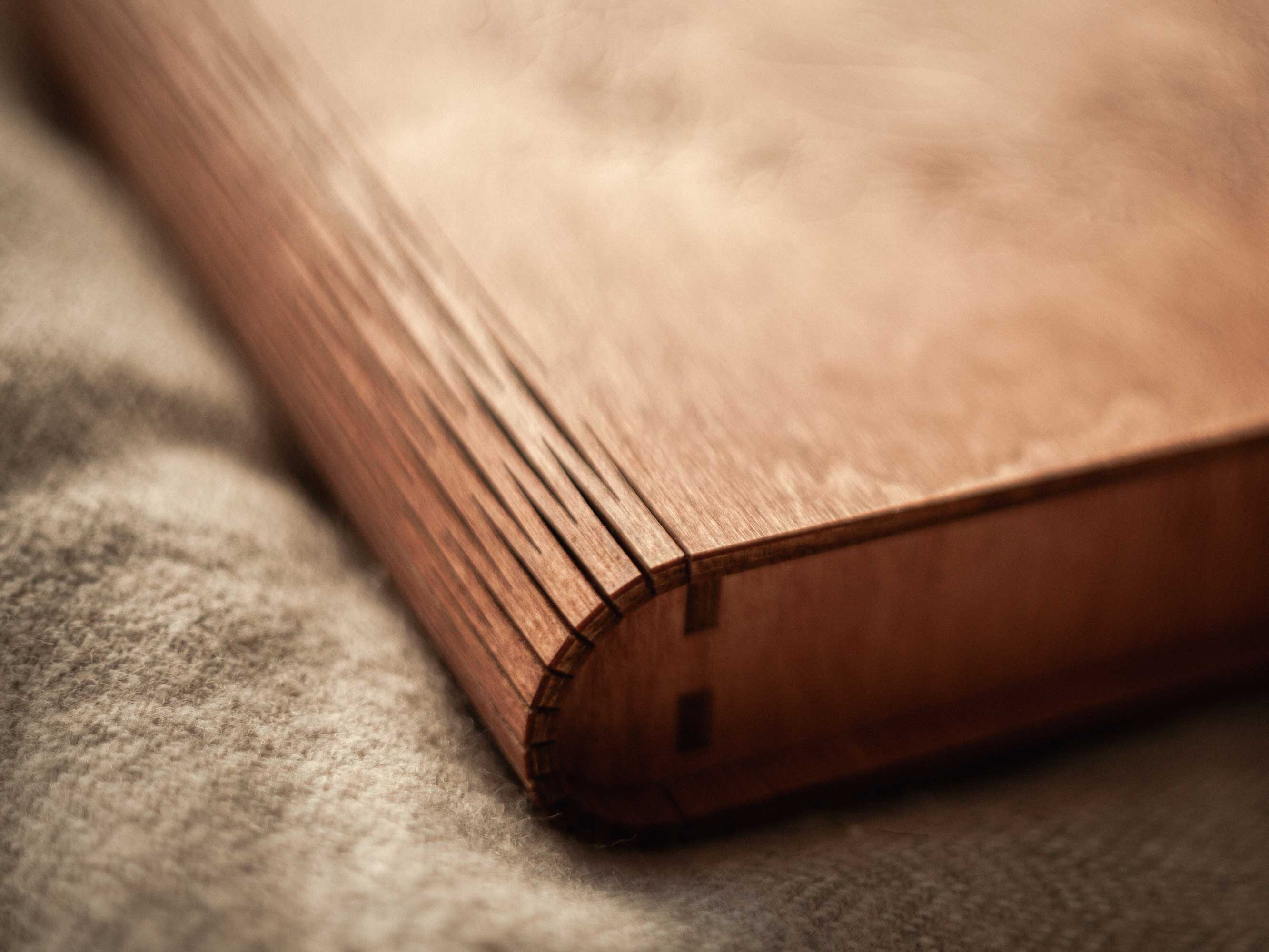 Side detail of teak wooden photo box with curved lid and wood grain
