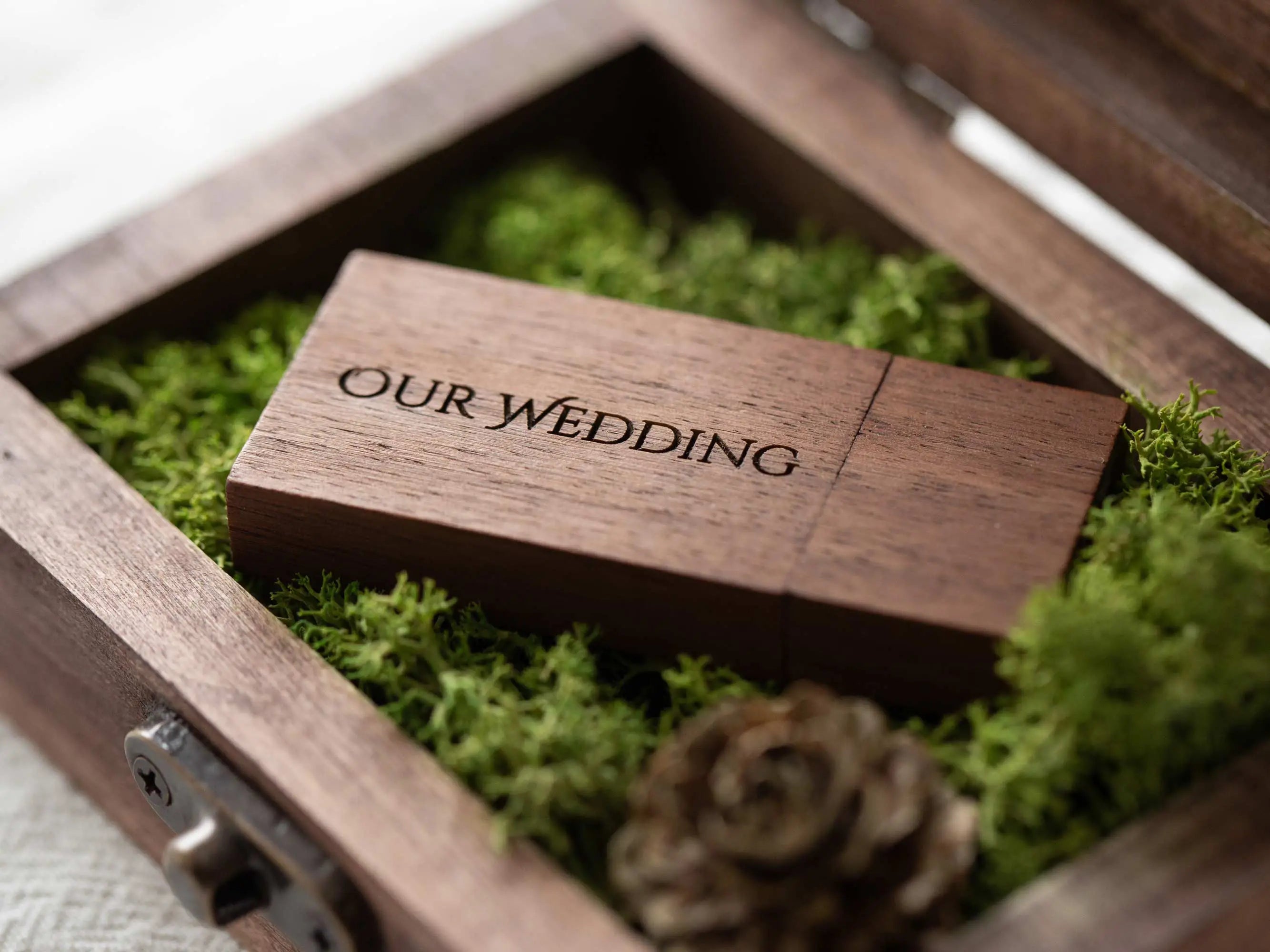 Open wooden USB box with green moss insert and engraved “Our Wedding” wood flash drive.