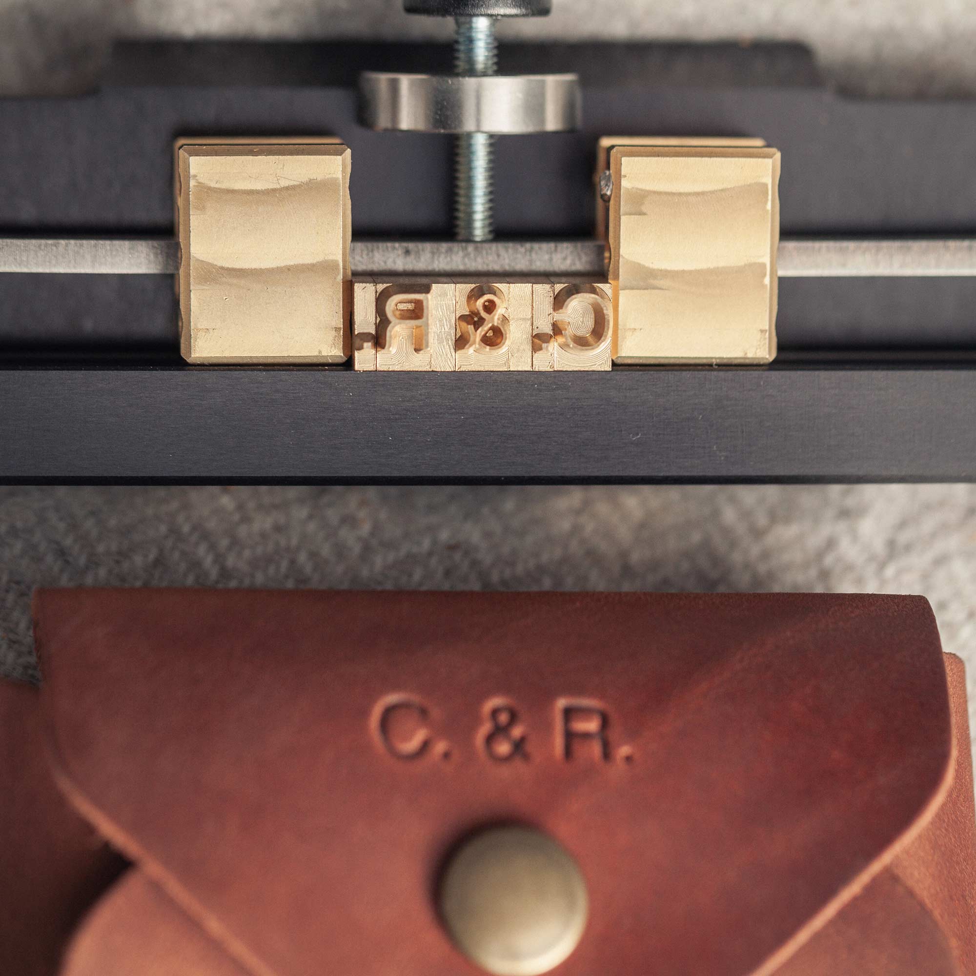 Close-up of brass letters inside hot stamping machine for leather personalization