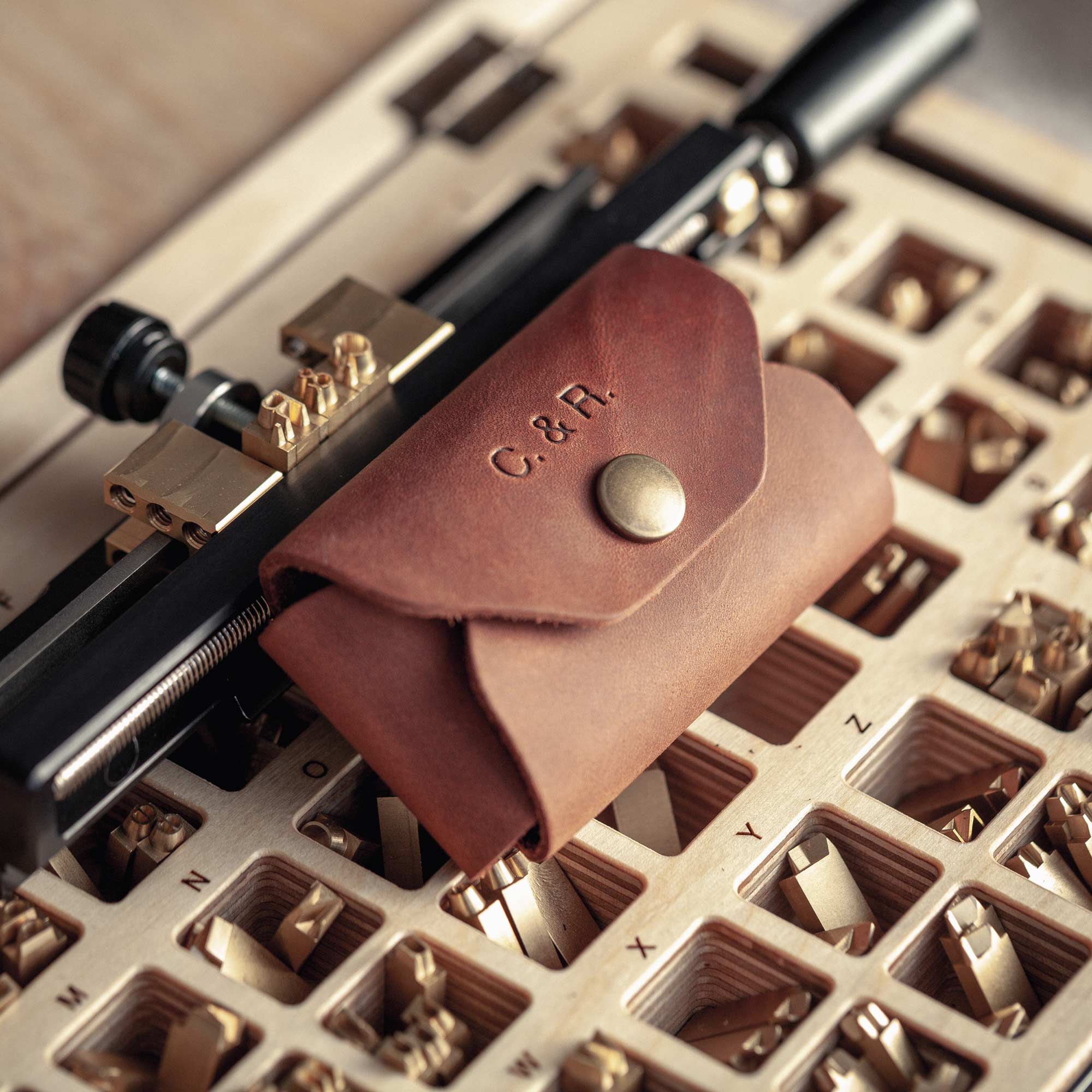Detail of hot-stamped initials on cognac leather USB pouch