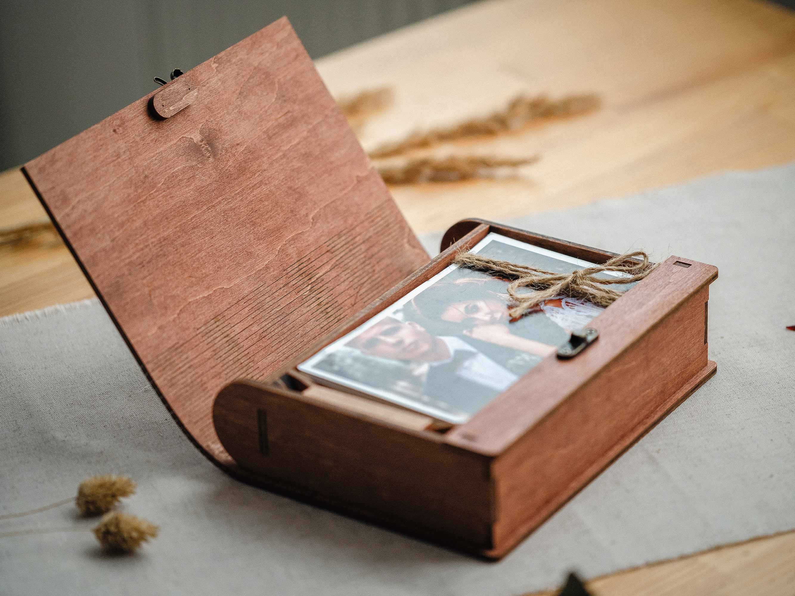 Open teak wooden wedding photo box with prints inside and jute twine, client reveal setup