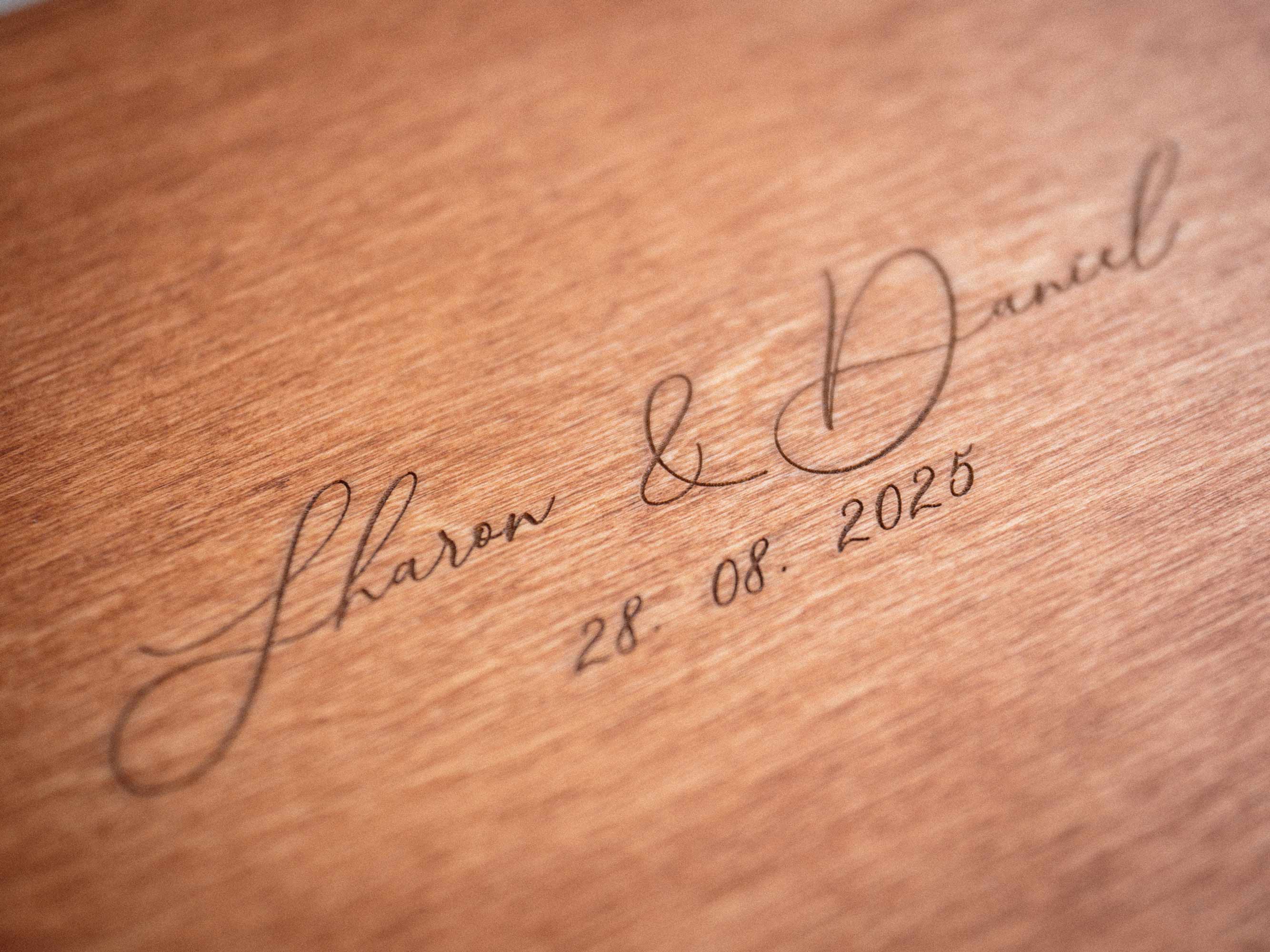 Close up of personalized engraving on teak wedding photo box lid