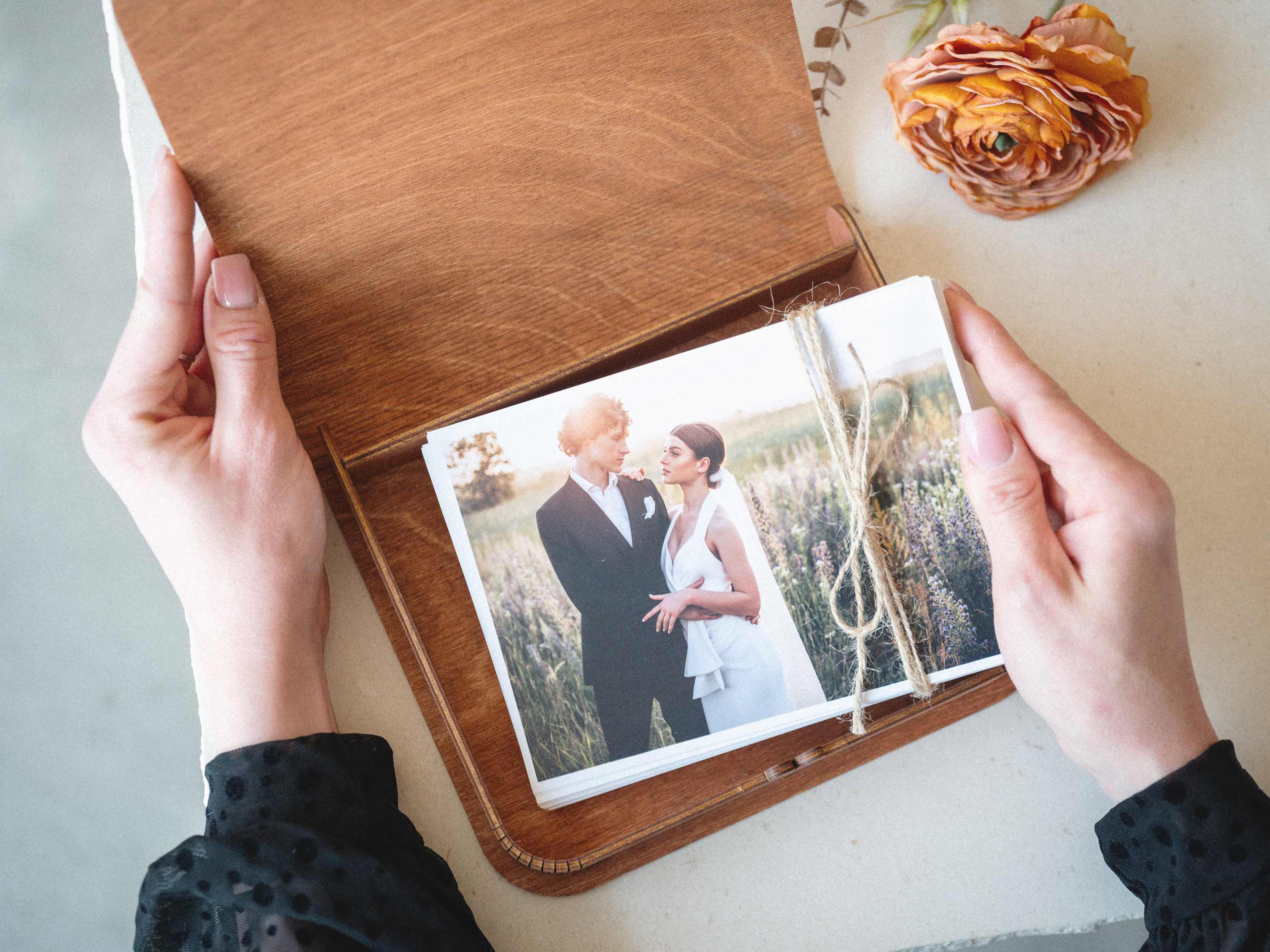 Open teak wooden photo box with wedding prints viewed from above