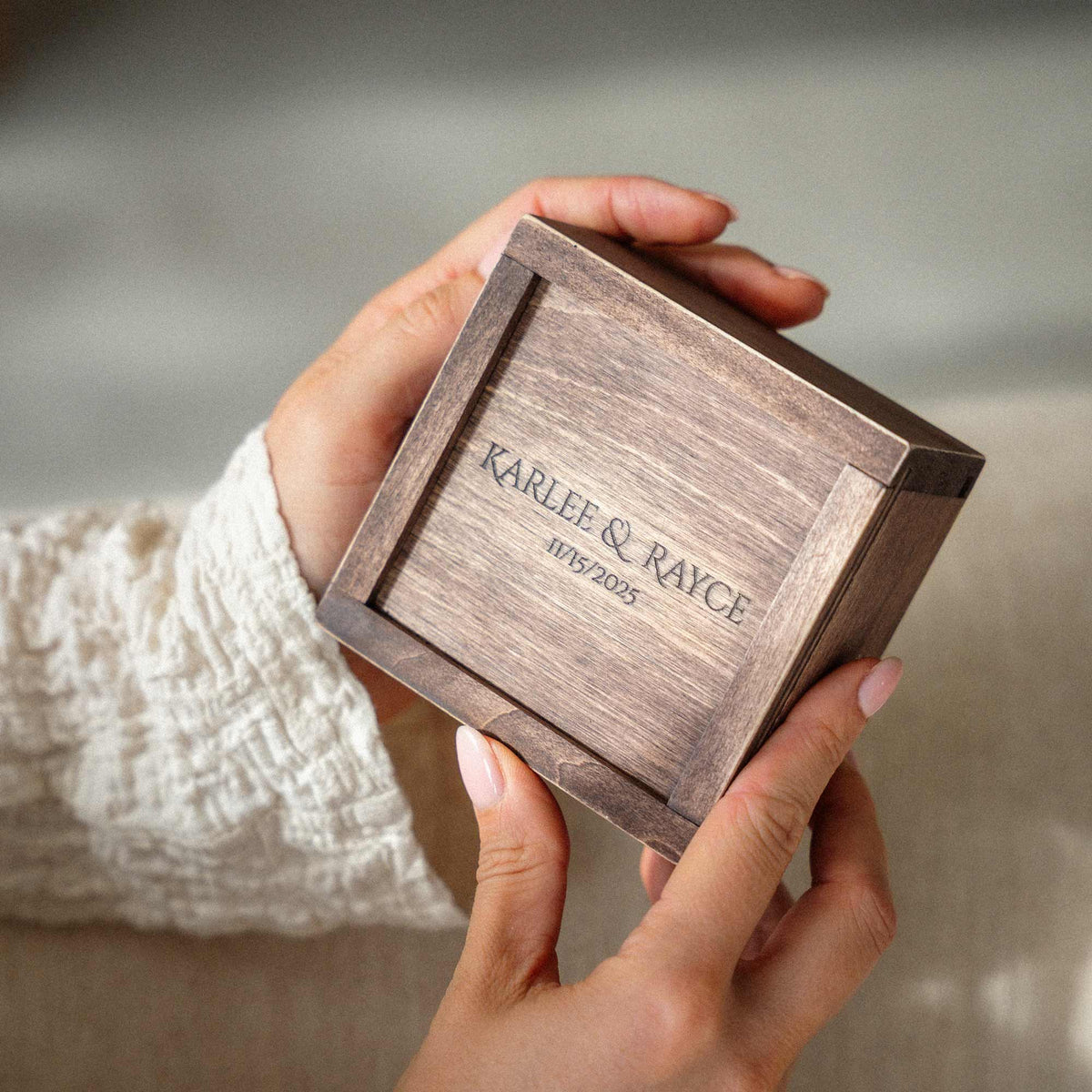 Hand holding a custom engraved wooden USB presentation box for wedding photos and photographer client delivery.
