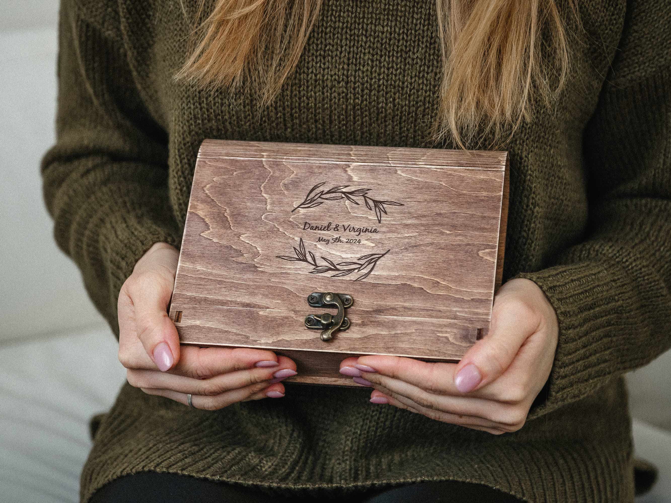 Person holding engraved vintage walnut photo box, premium photography packaging for wedding clients