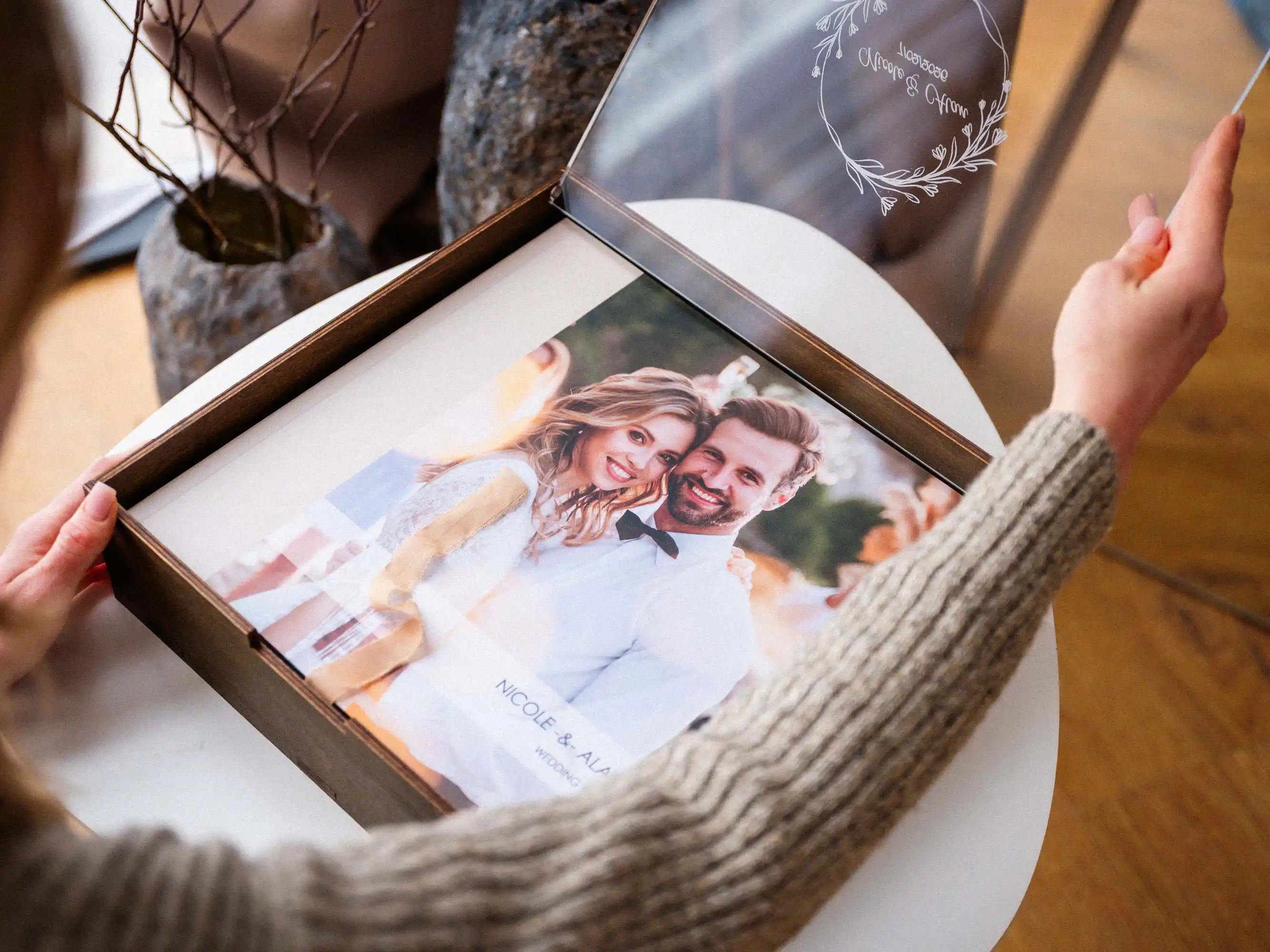 Hands opening walnut wedding album box with acrylic lid and printed album