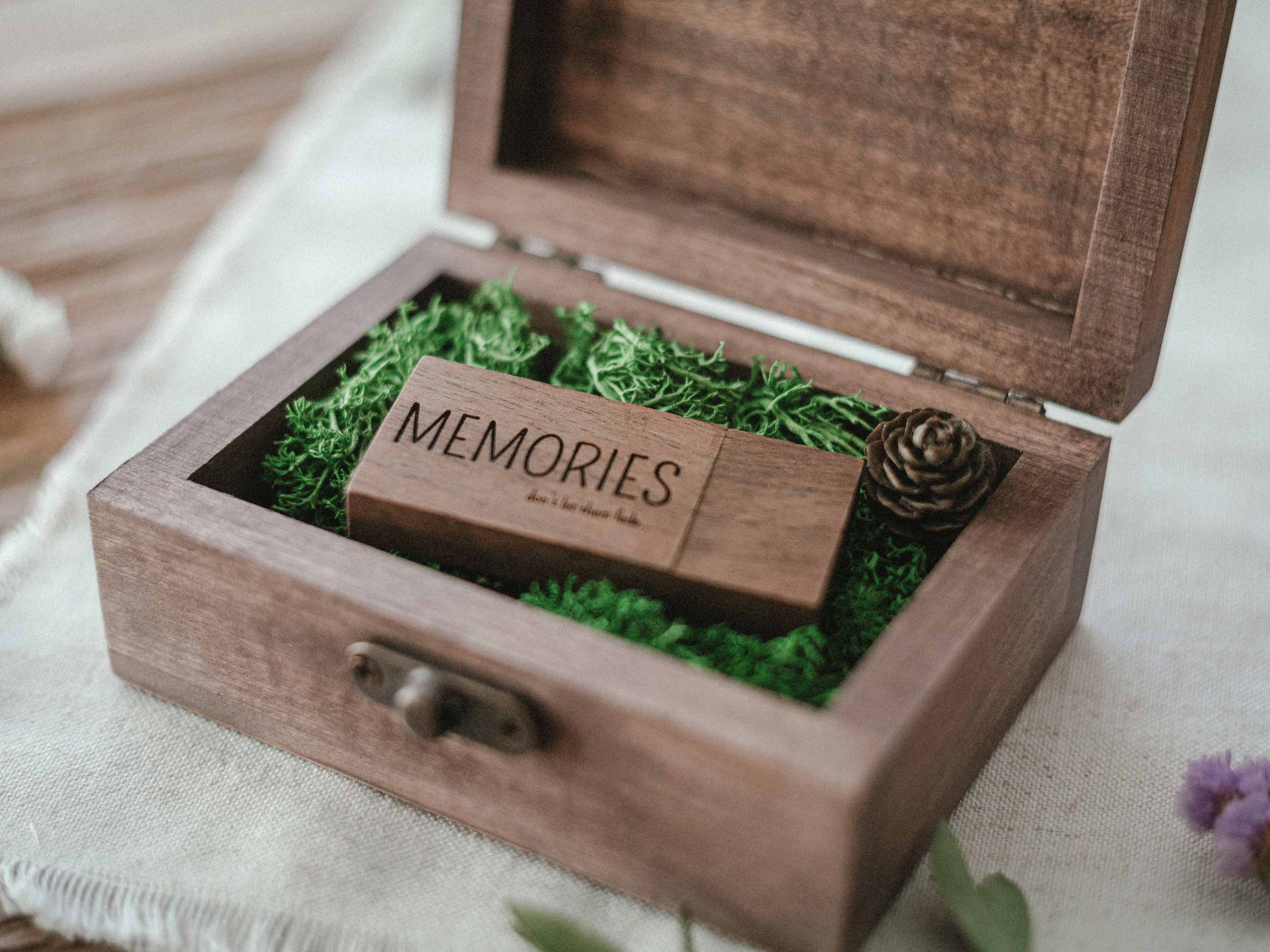 Open walnut wooden USB box with Memories flash drive and Scandinavian moss