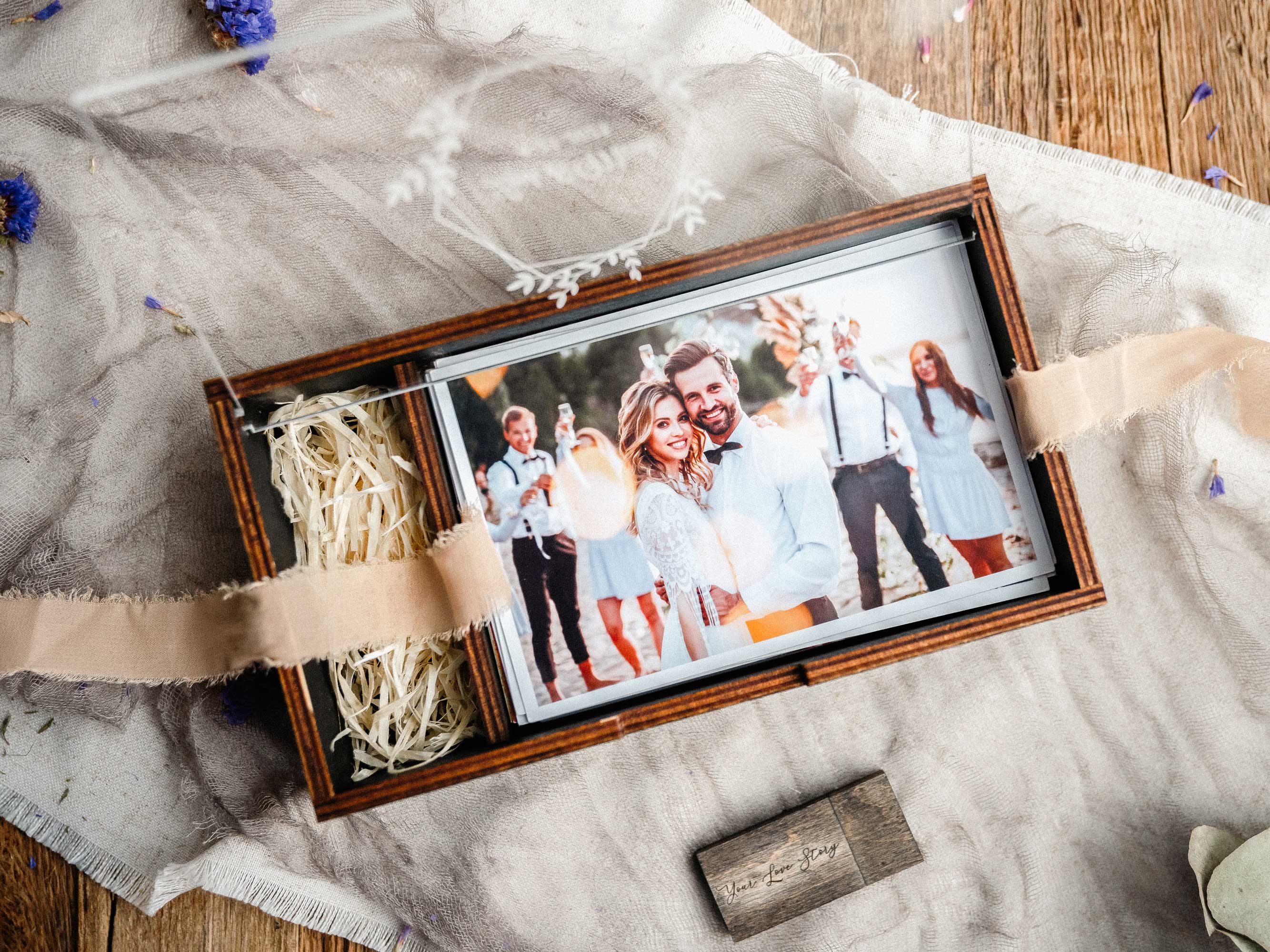 Black wedding photo box with wooden USB and tied photo prints flat lay
