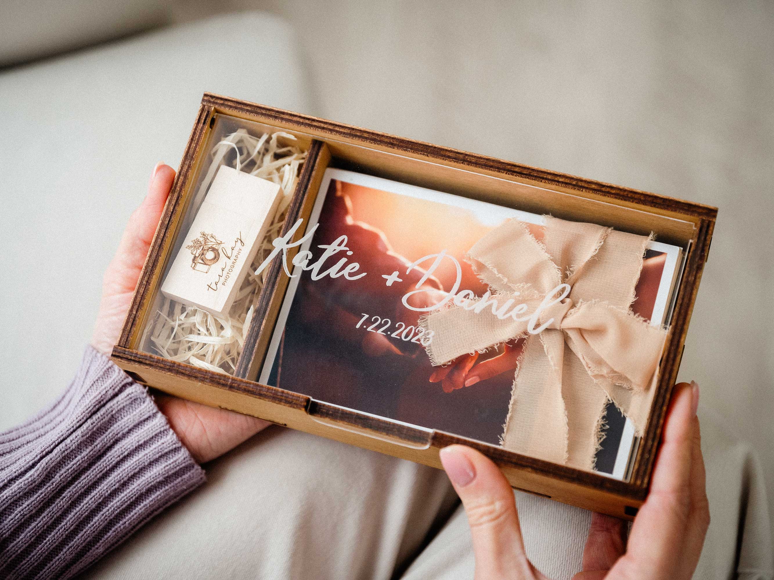 Gold Oak wedding photo box with USB, personalized acrylic lid, and tied wedding prints held in hands
