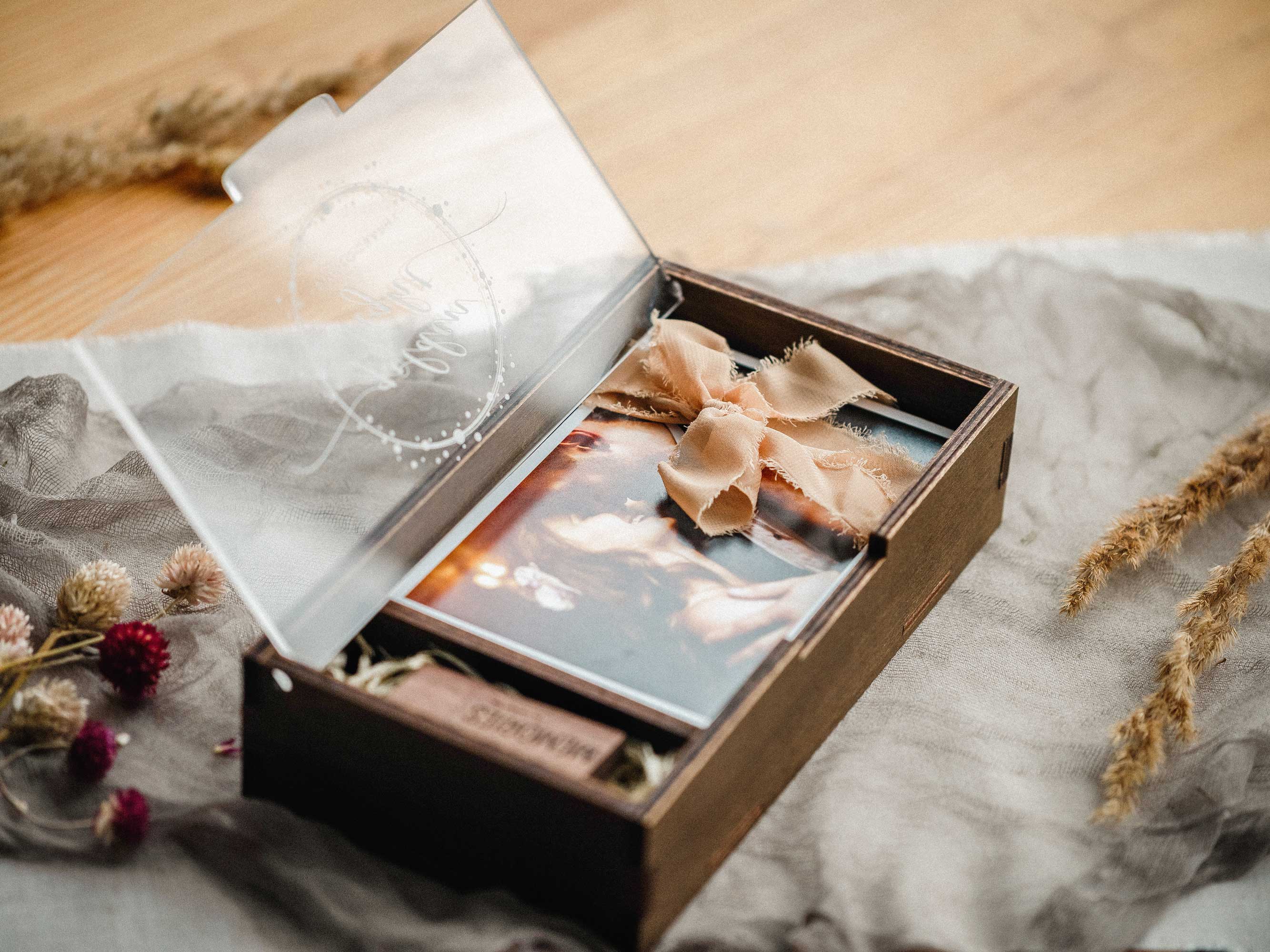 Detail of engraved acrylic lid on a wooden photo box with wedding print inside